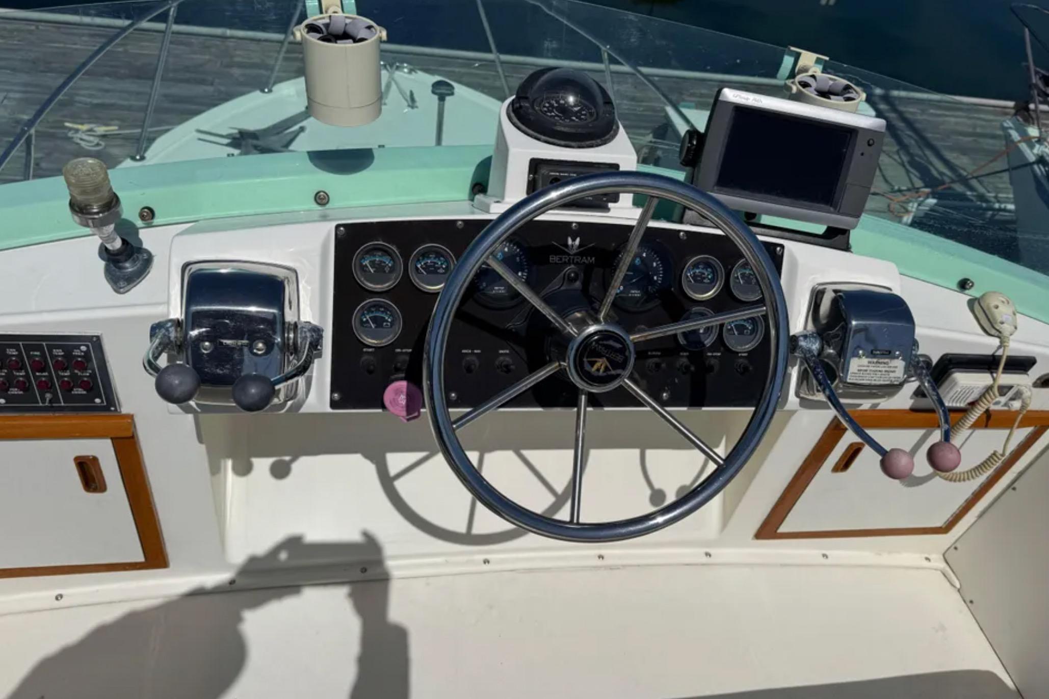 Control panel of a 1988 Bertram 28 Sport Fisherman boat with steering wheel and gauges.