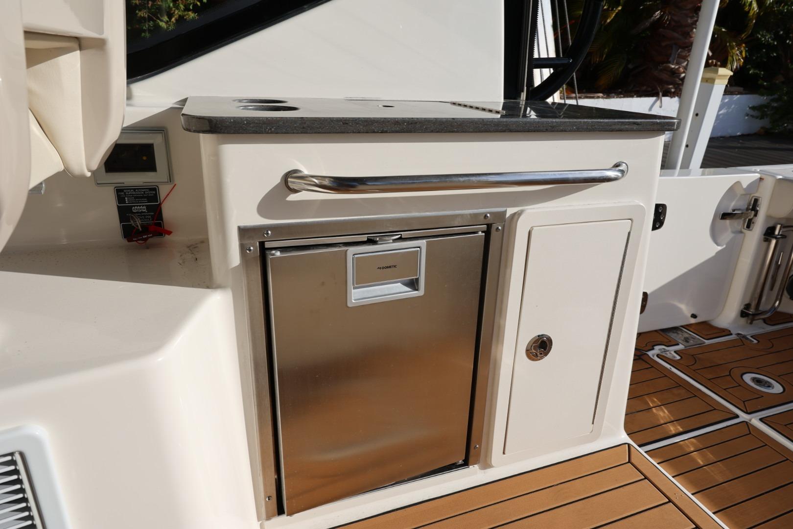 2025 Boston Whaler 325 Conquest boat interior with stainless steel fridge and storage compartments.
