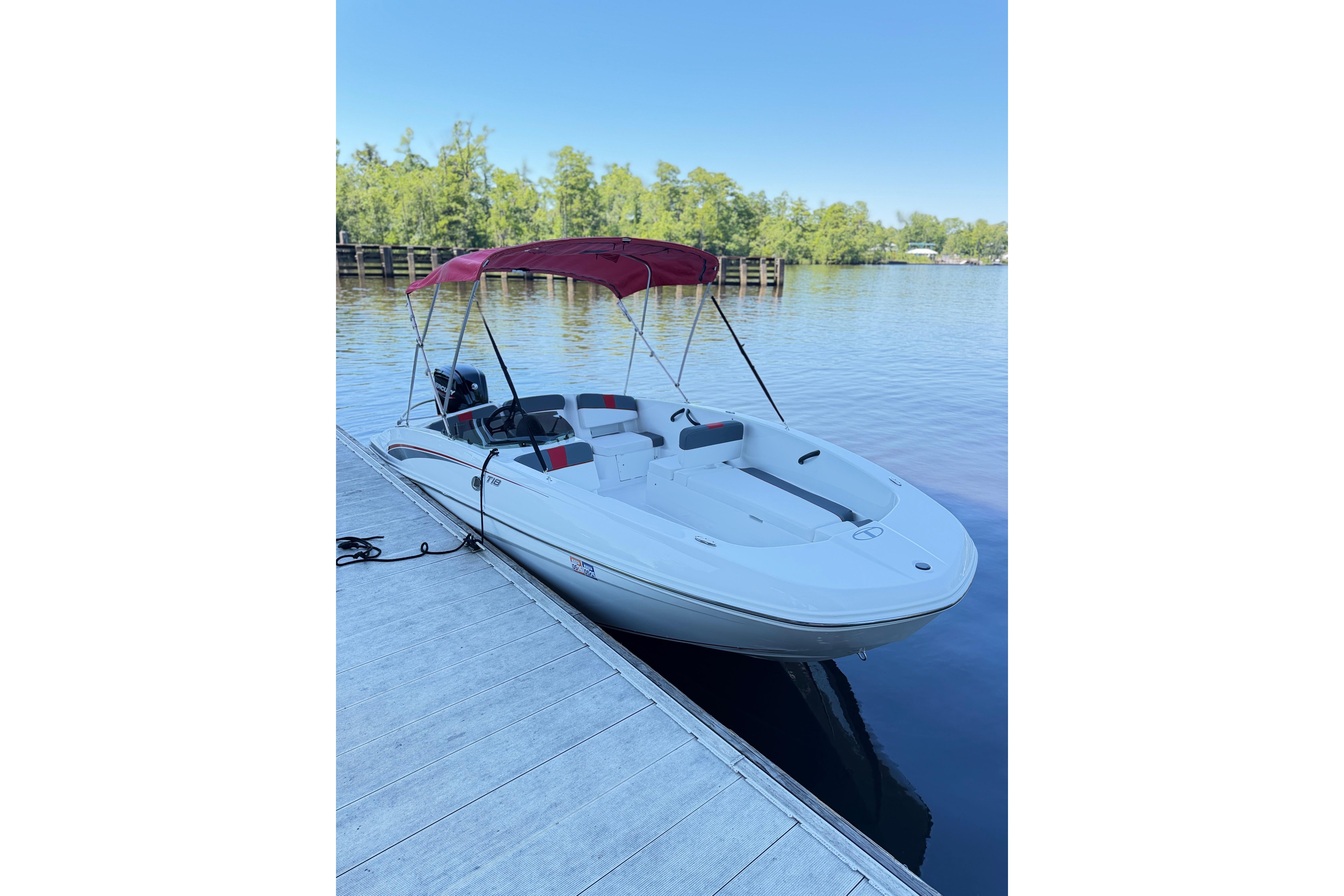 2022 Tahoe T18 boat docked on a serene lake with a red canopy.