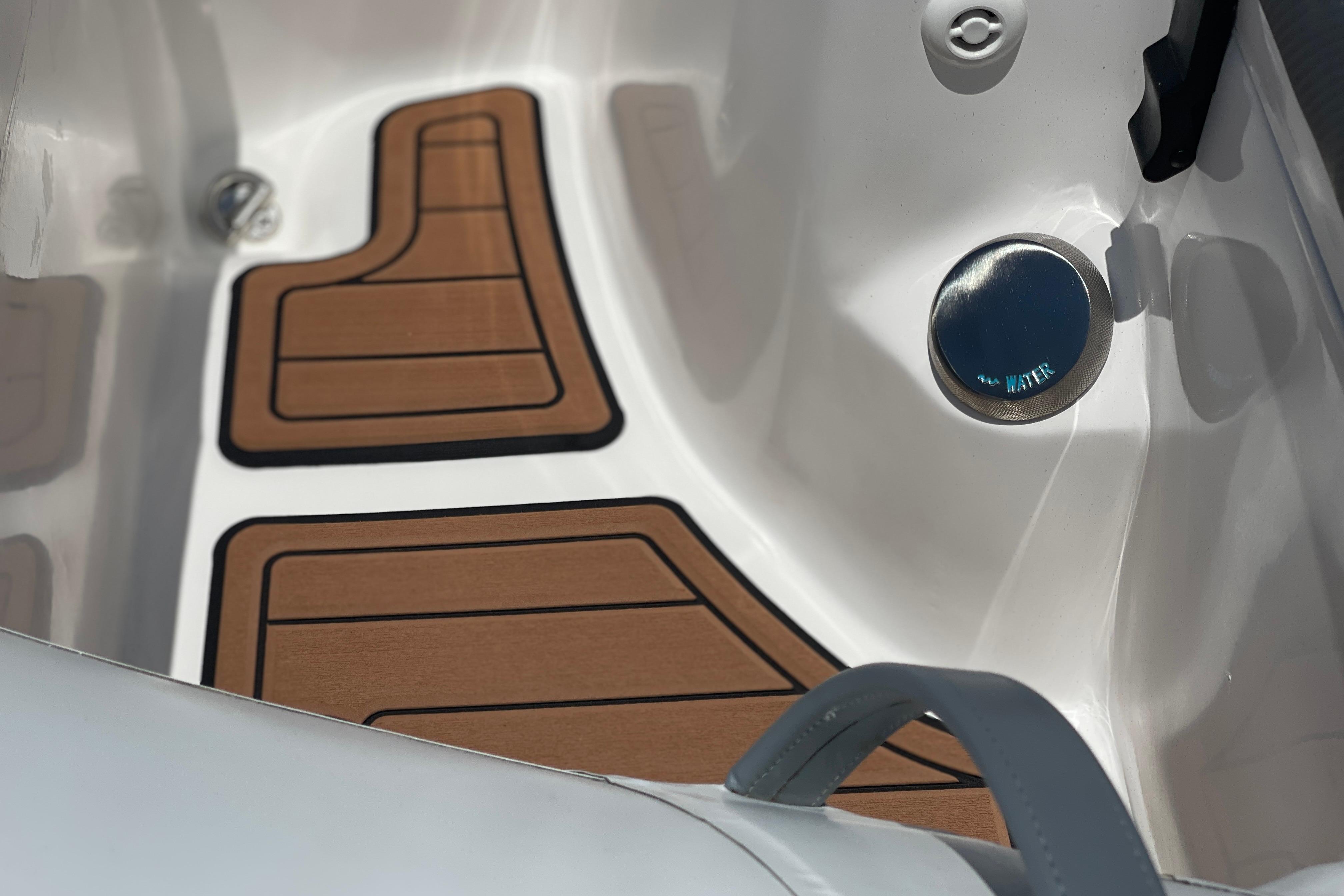 Interior of 2025 Caribe DL11 boat with wooden floor mats and water cap.