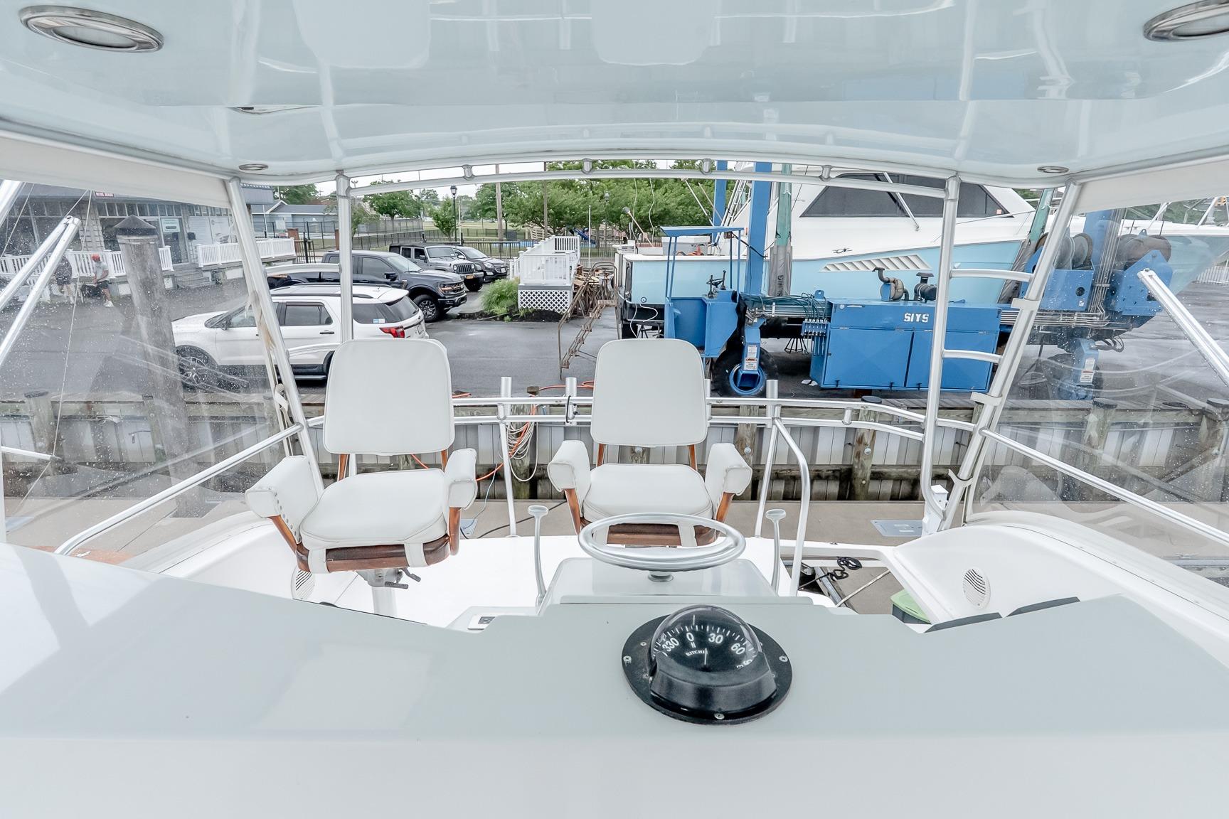 Helm of 2000 Viking 50' Convertible yacht with white captain chairs and compass.