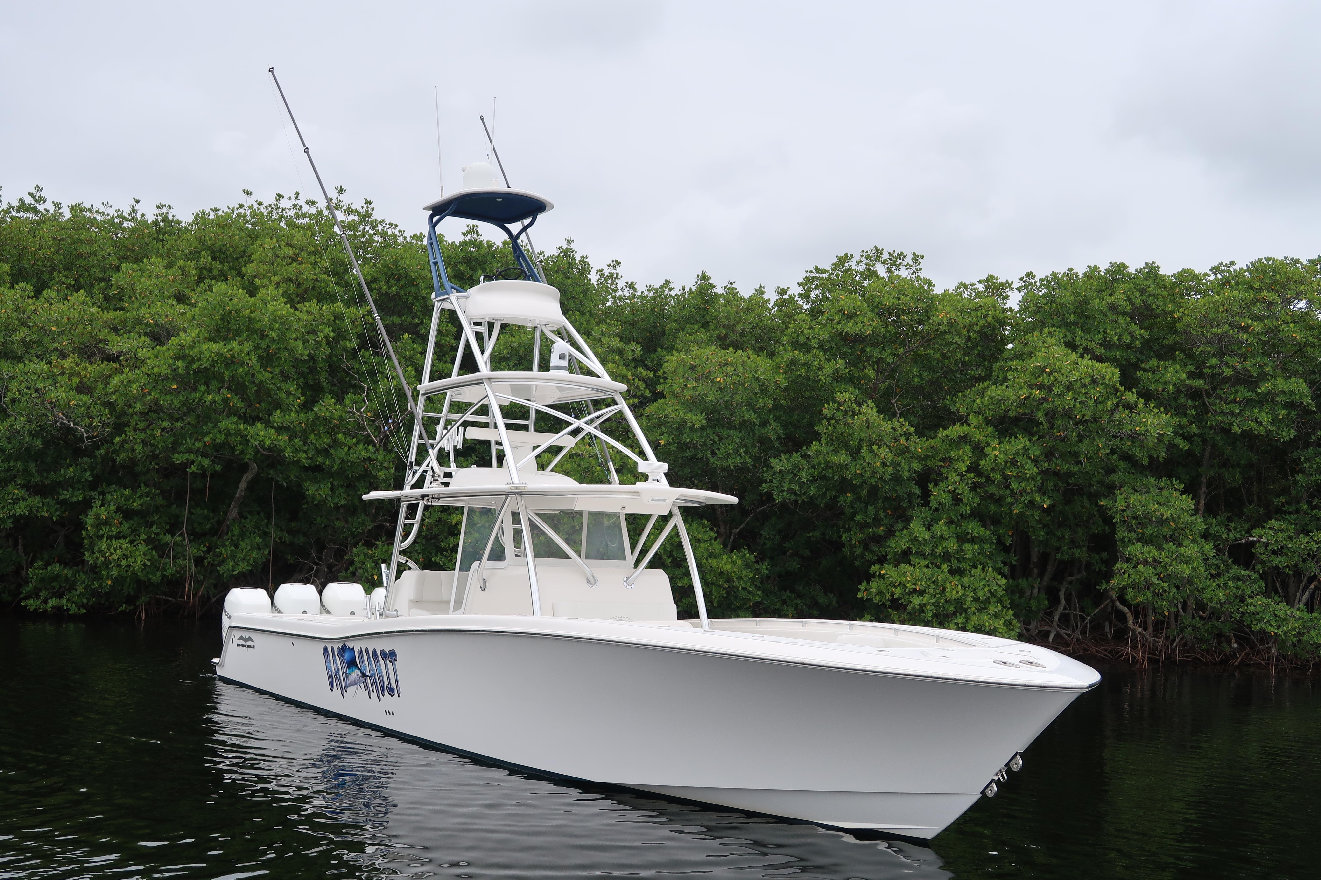 2016 Invincible 42 Open Fisherman boat on calm water near lush greenery.