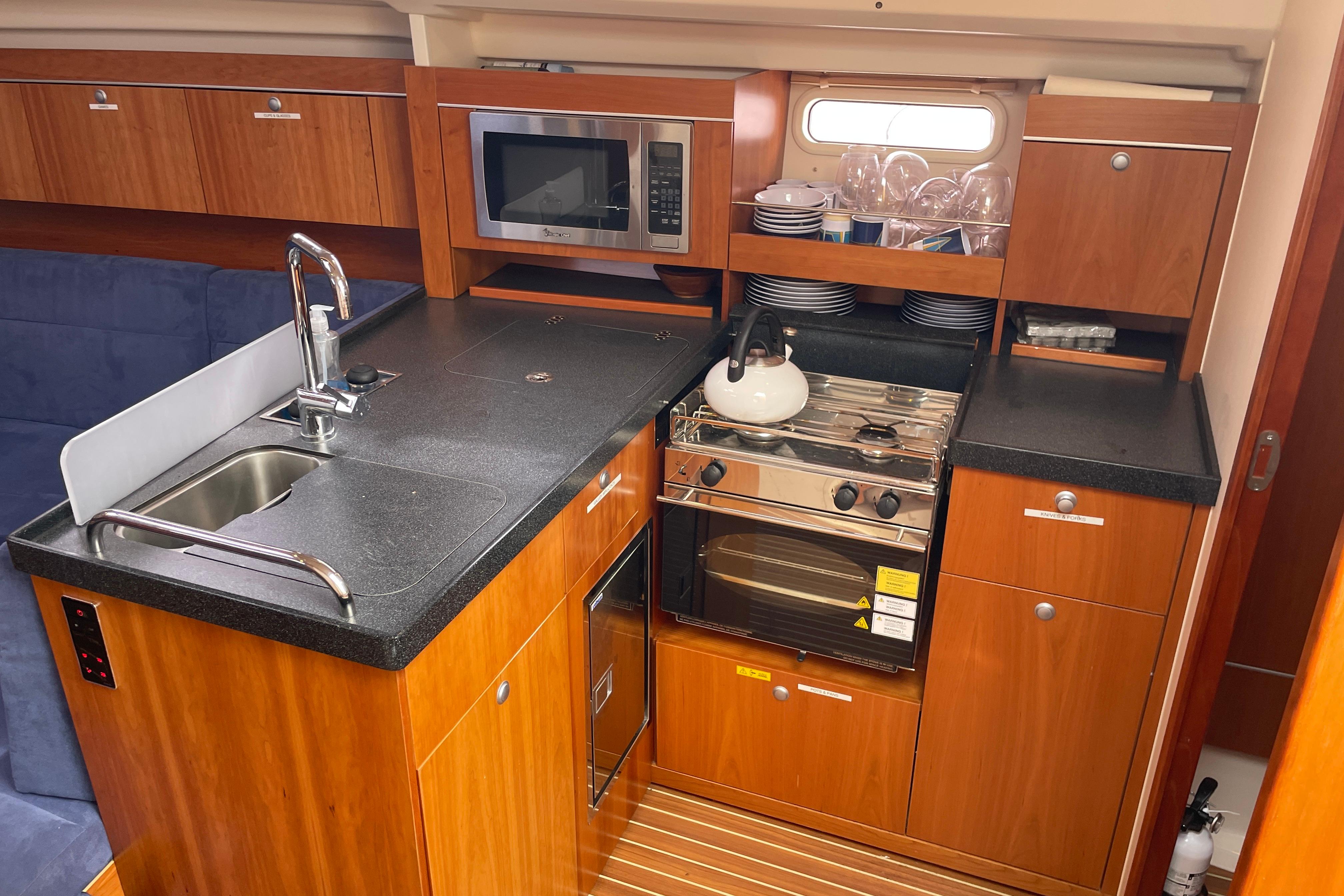 Compact kitchen in a 2014 Hanse 415 yacht with stove, sink, and microwave.