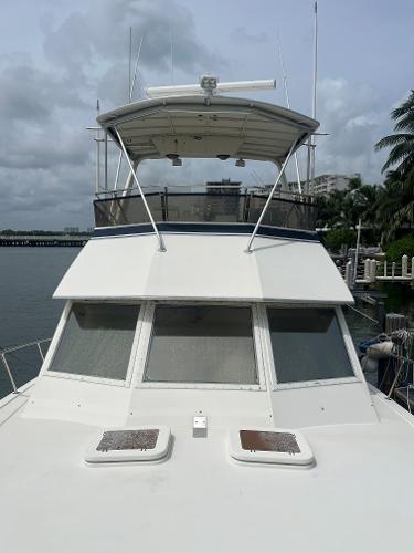 1985 Hatteras 45 Convertible yacht docked, front view with flybridge and windows.
