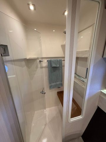 Interior view of a modern boat shower with glass walls and towel rack.