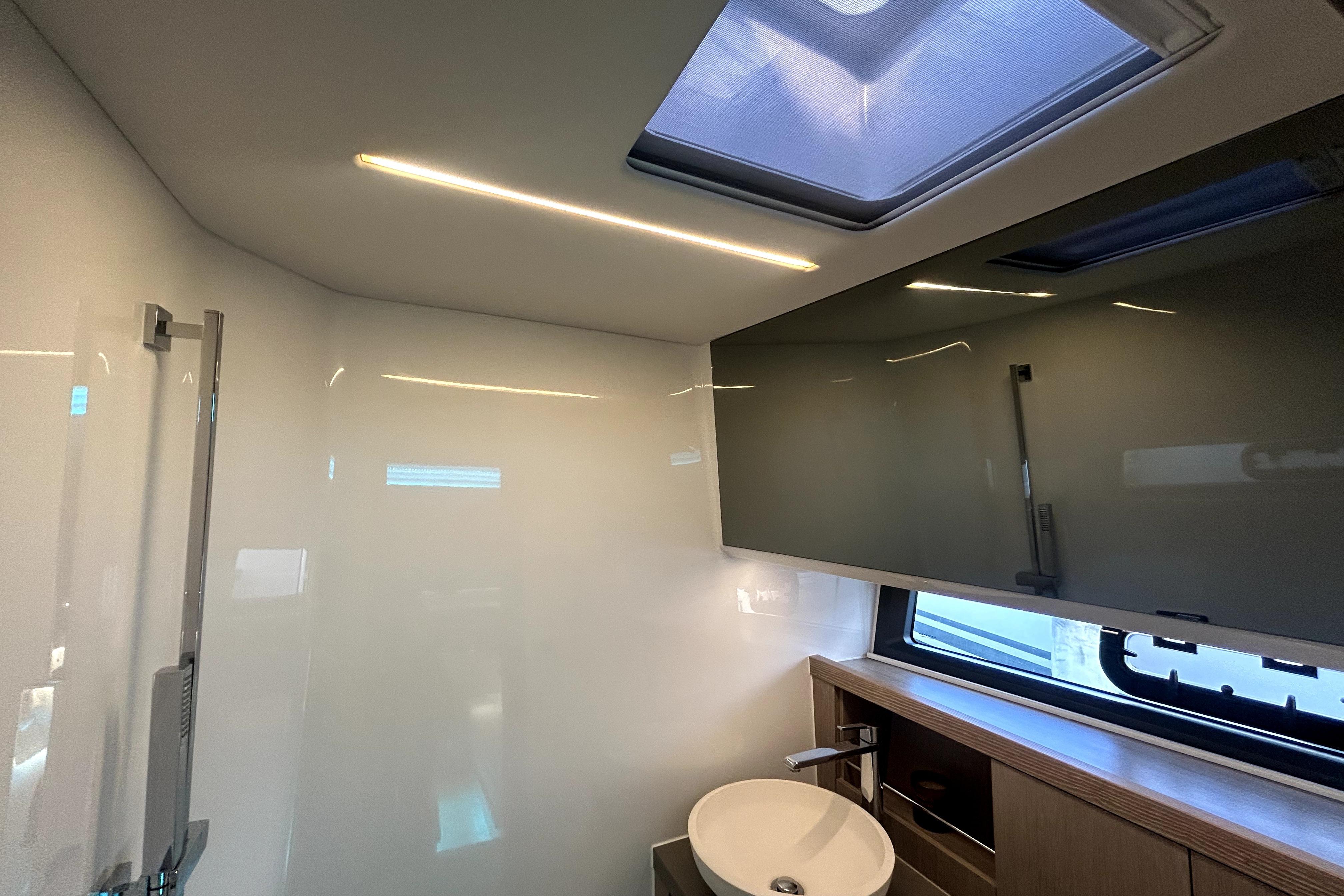 Modern bathroom interior of 2023 Fjord 53 XL yacht with sleek design and skylight.