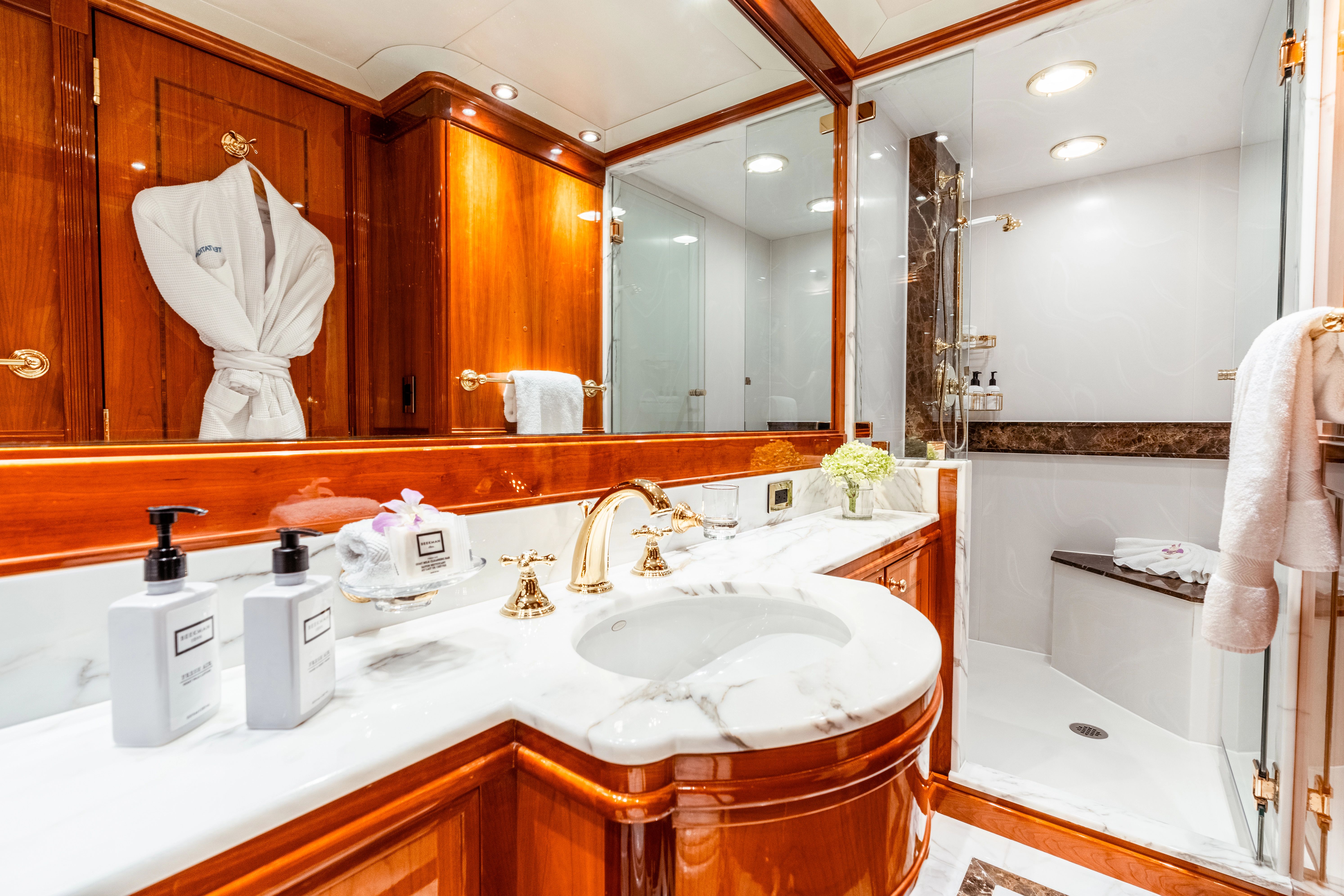 Luxurious bathroom with marble countertop, gold fixtures, and a large shower in a yacht.
