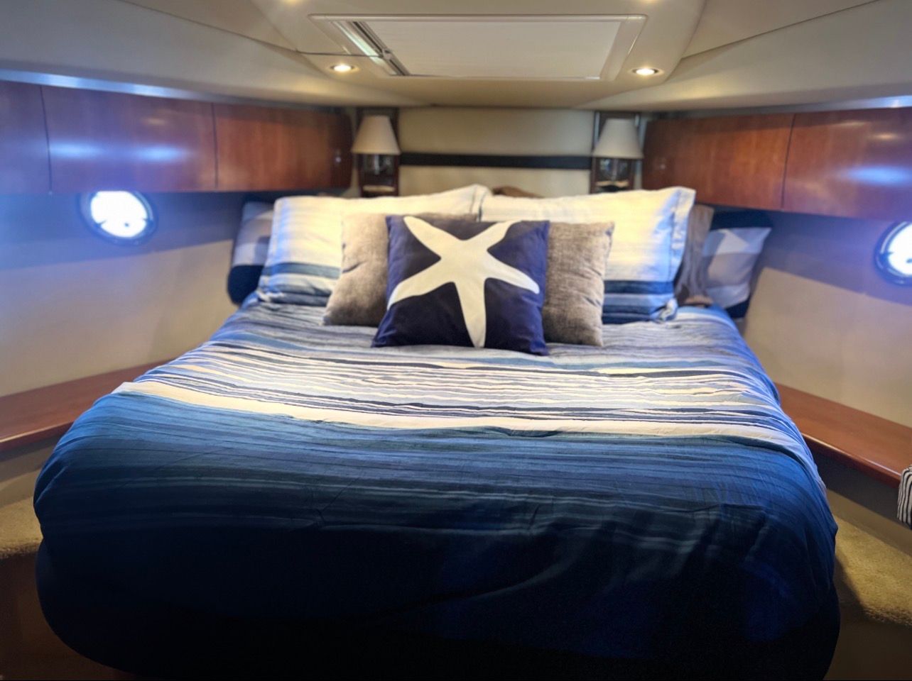 The image shows a cozy cabin with a large bed, decorated with blue stripes and a starfish pillow.
