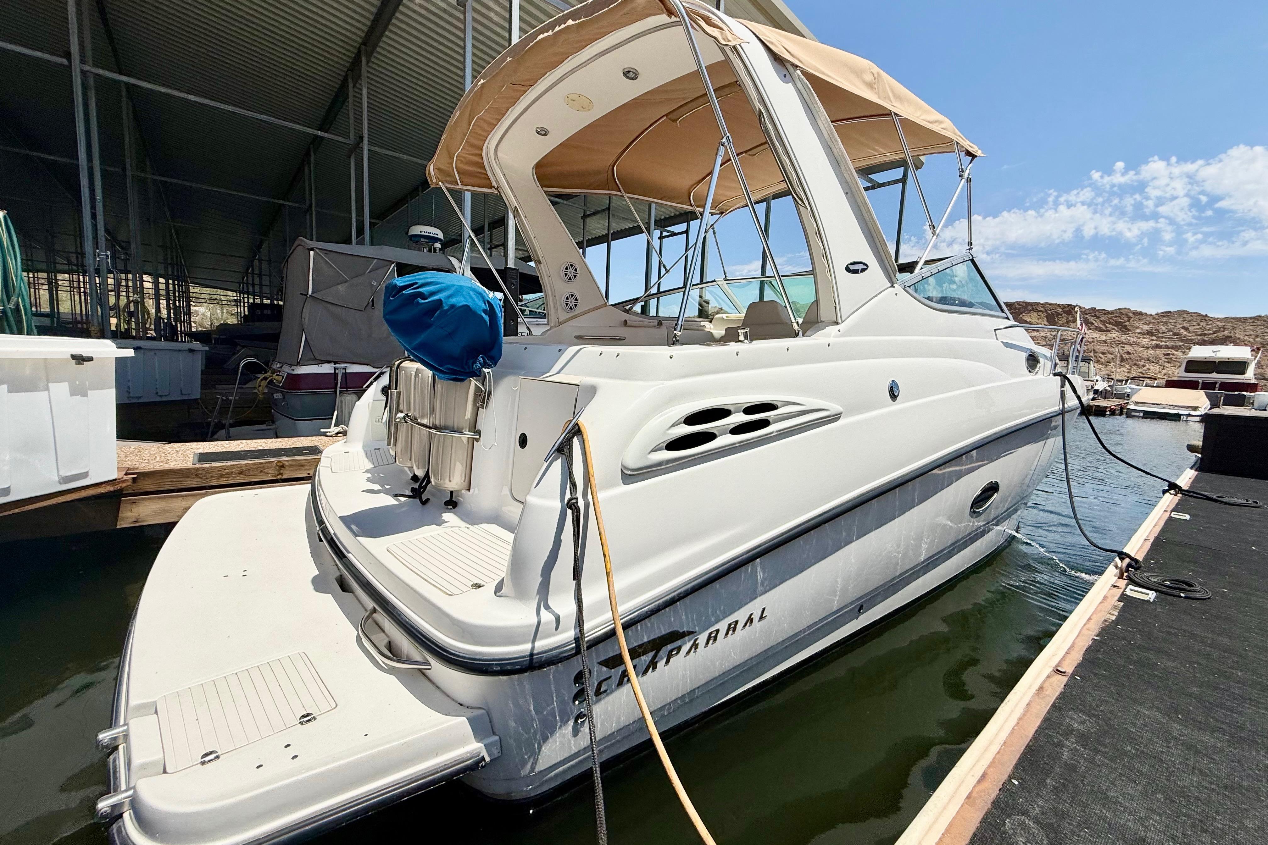 1999 Chaparral Signature 300 boat docked, featuring a beige canopy and sleek design.