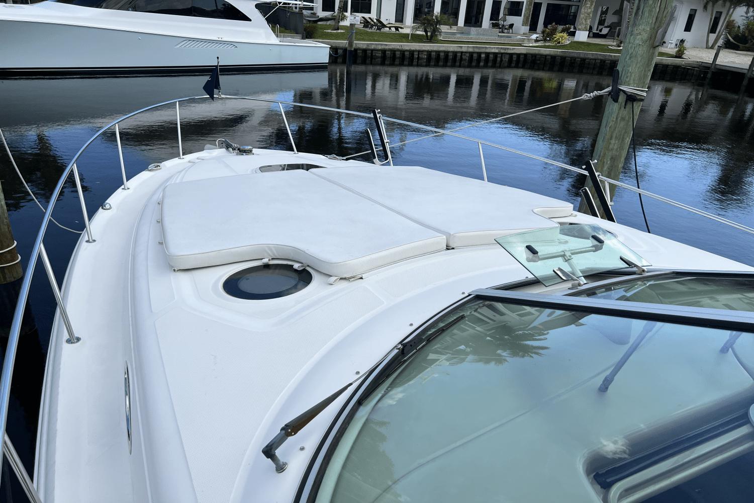 2005 Sea Ray 340 Sundancer boat with sunpad on deck, docked by calm waters.