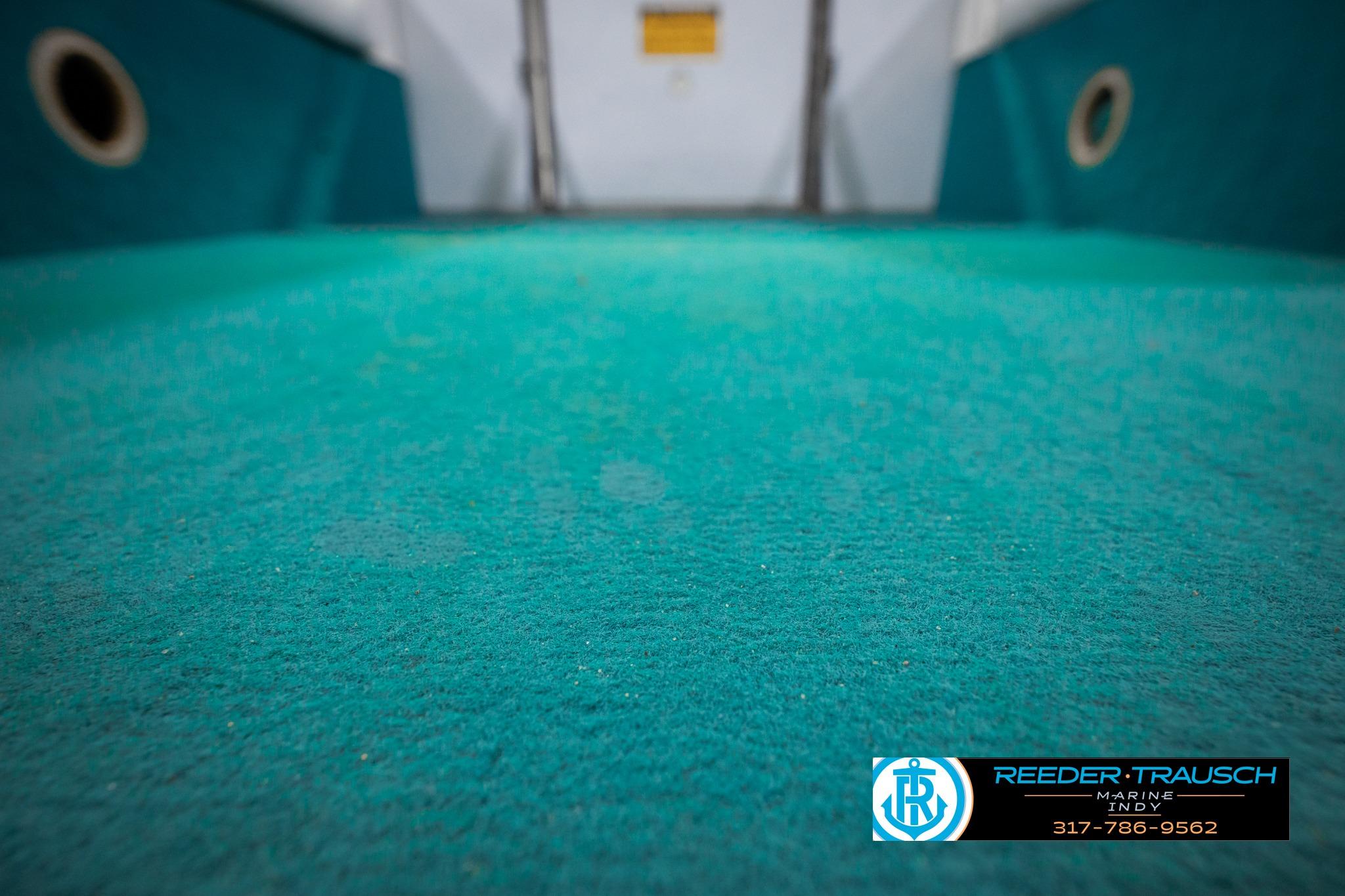 Turquoise carpeted interior of a 1992 Godfrey Sweetwater boat, featuring circular vents.