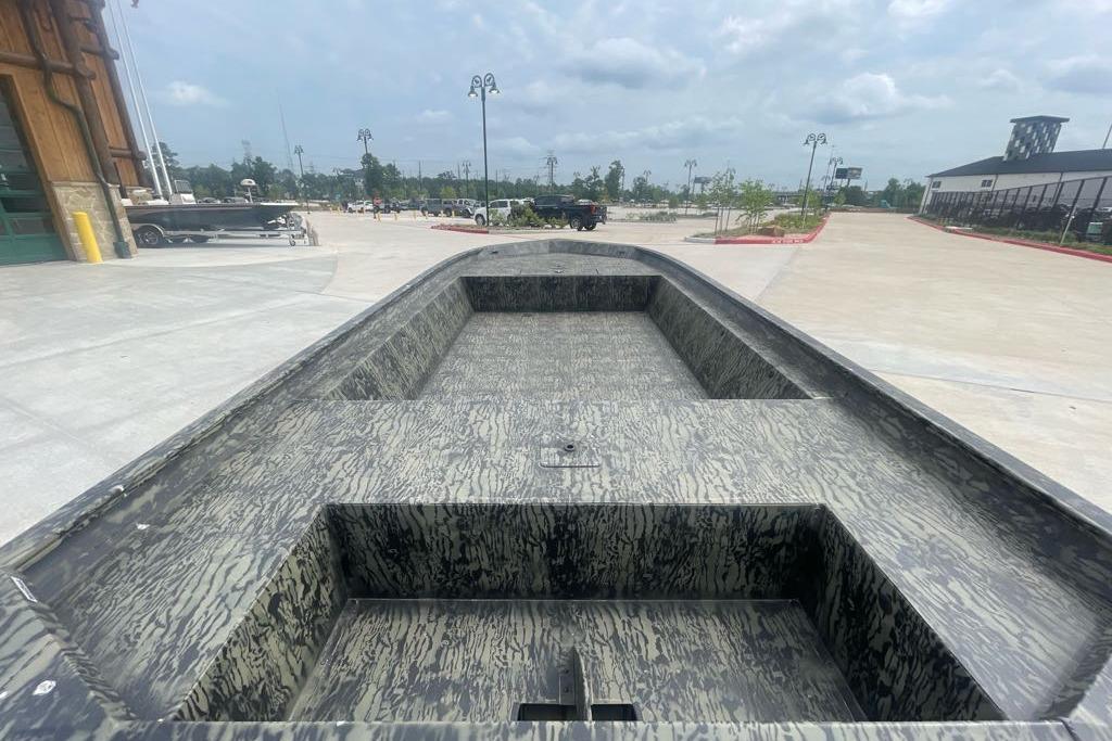 2025 Tracker Grizzly 1860 Utility boat with camouflage interior, parked outdoors.