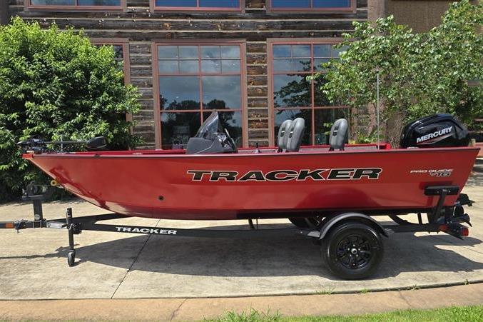 2026 Tracker Pro Guide V-16 SC boat in red, parked outdoors with Mercury engine.