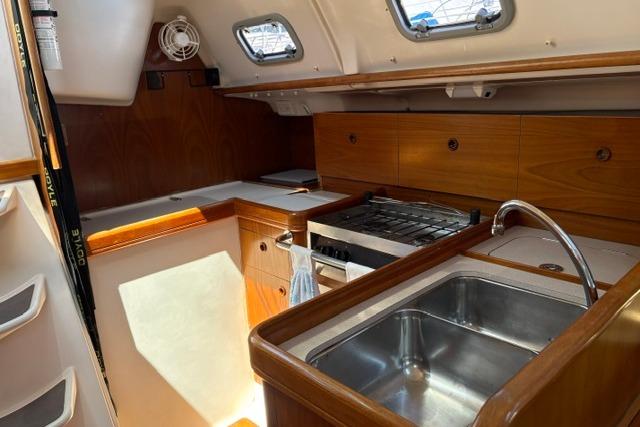 Interior of 2000 Beneteau Oceanis 321 yacht, featuring a compact kitchen with sink and stove.