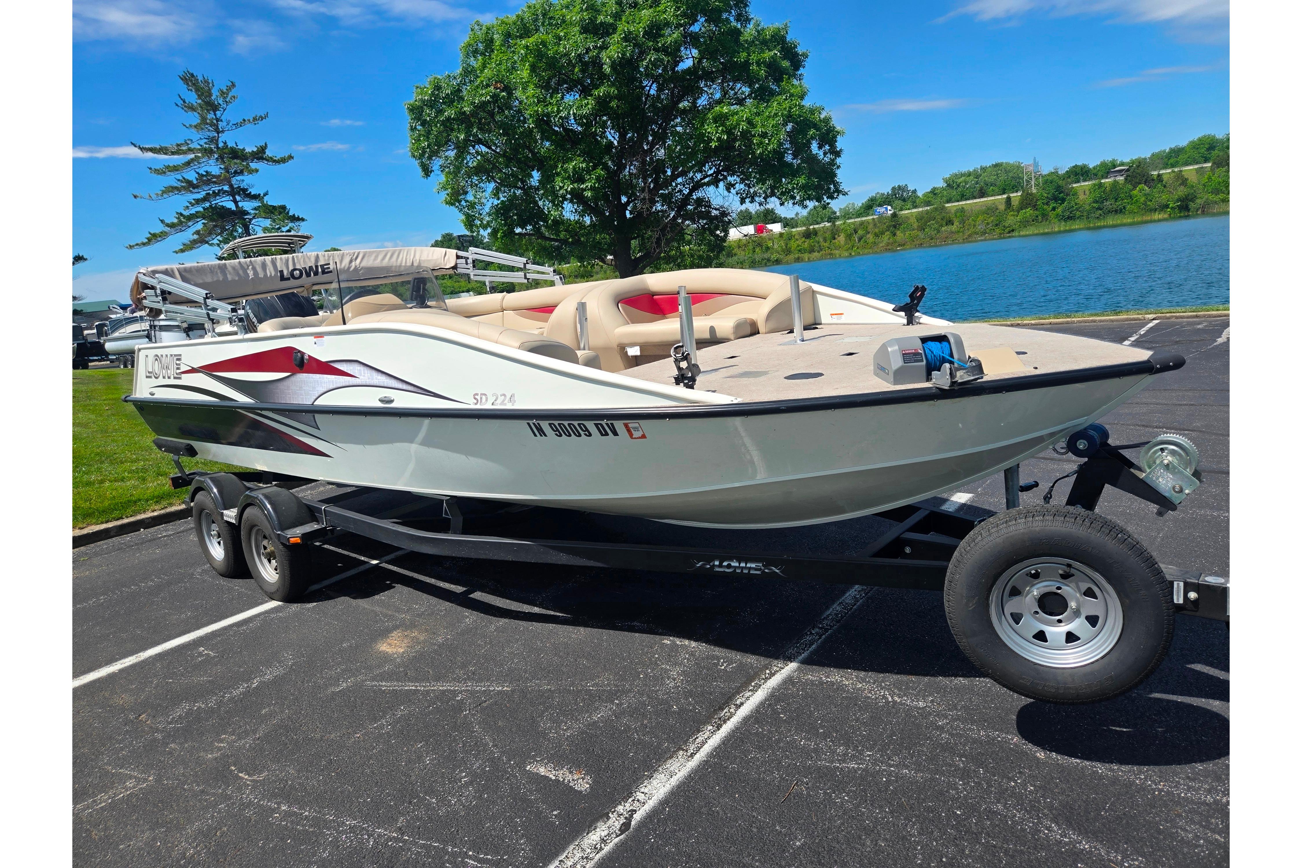 2015 Lowe Sport Deck 224 boat on trailer by a lake, sunny day.
