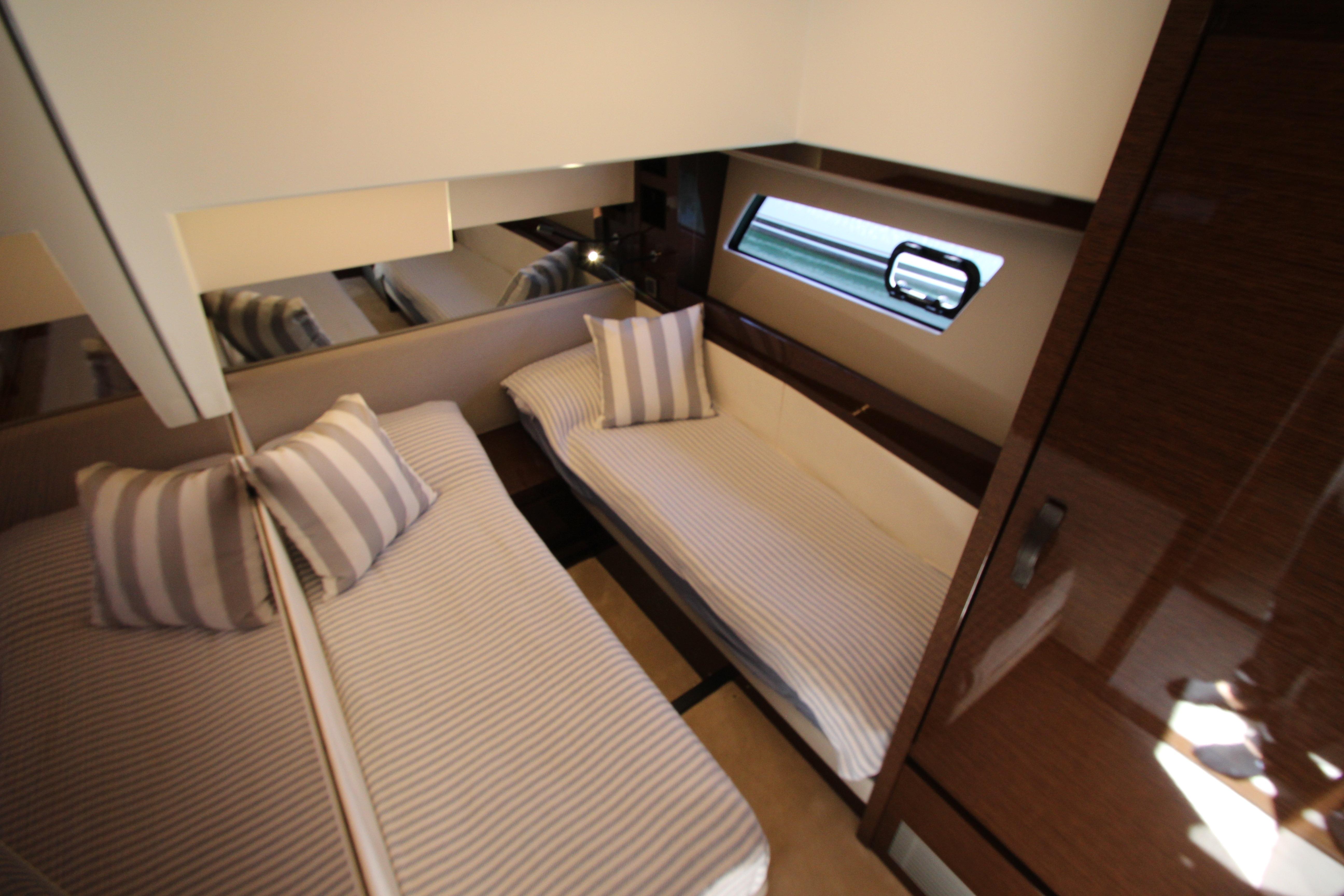 Luxurious twin cabin interior of 2022 Prestige 520 yacht with striped bedding.