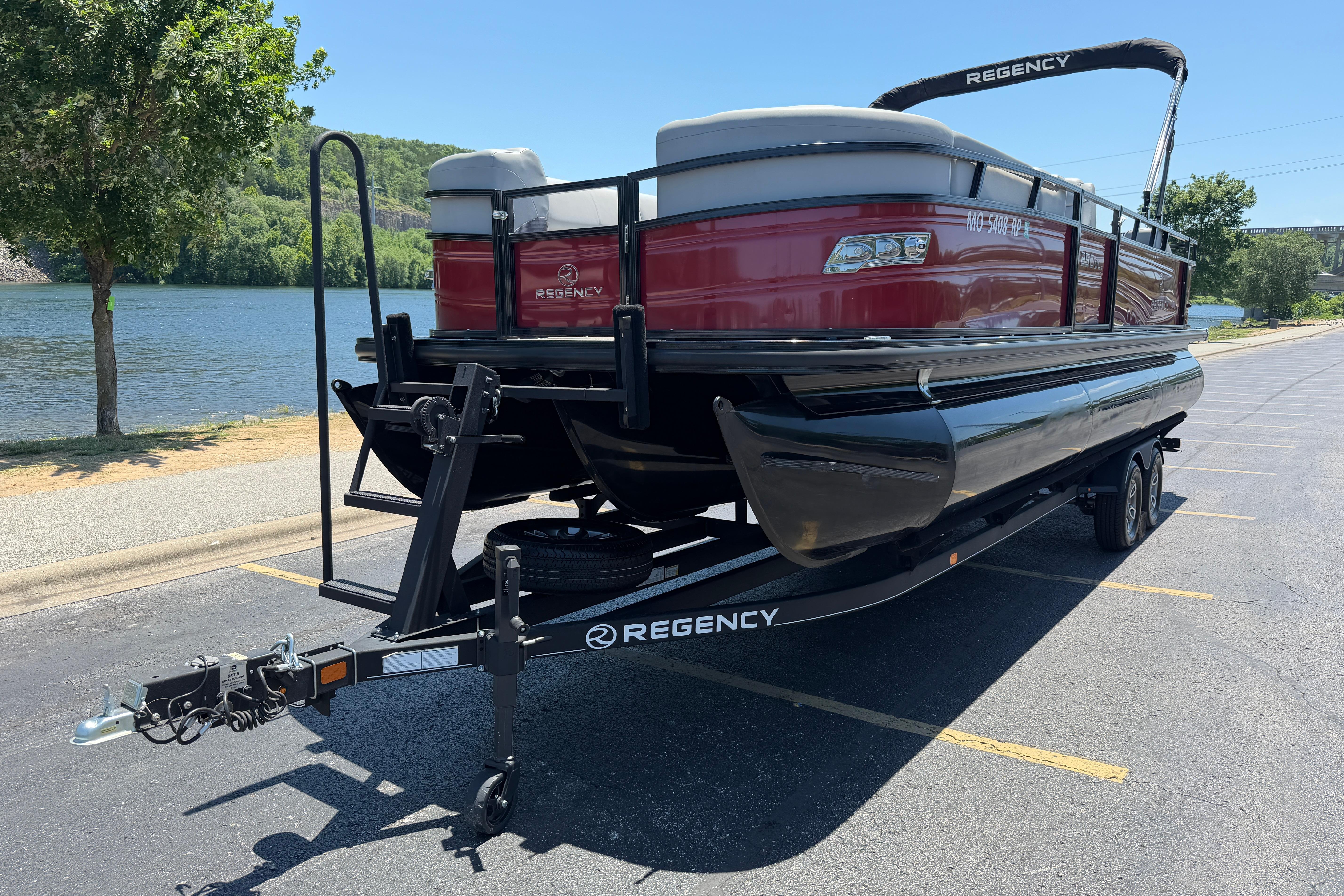 2024 Regency R250DL3 pontoon boat on trailer by a scenic lake.