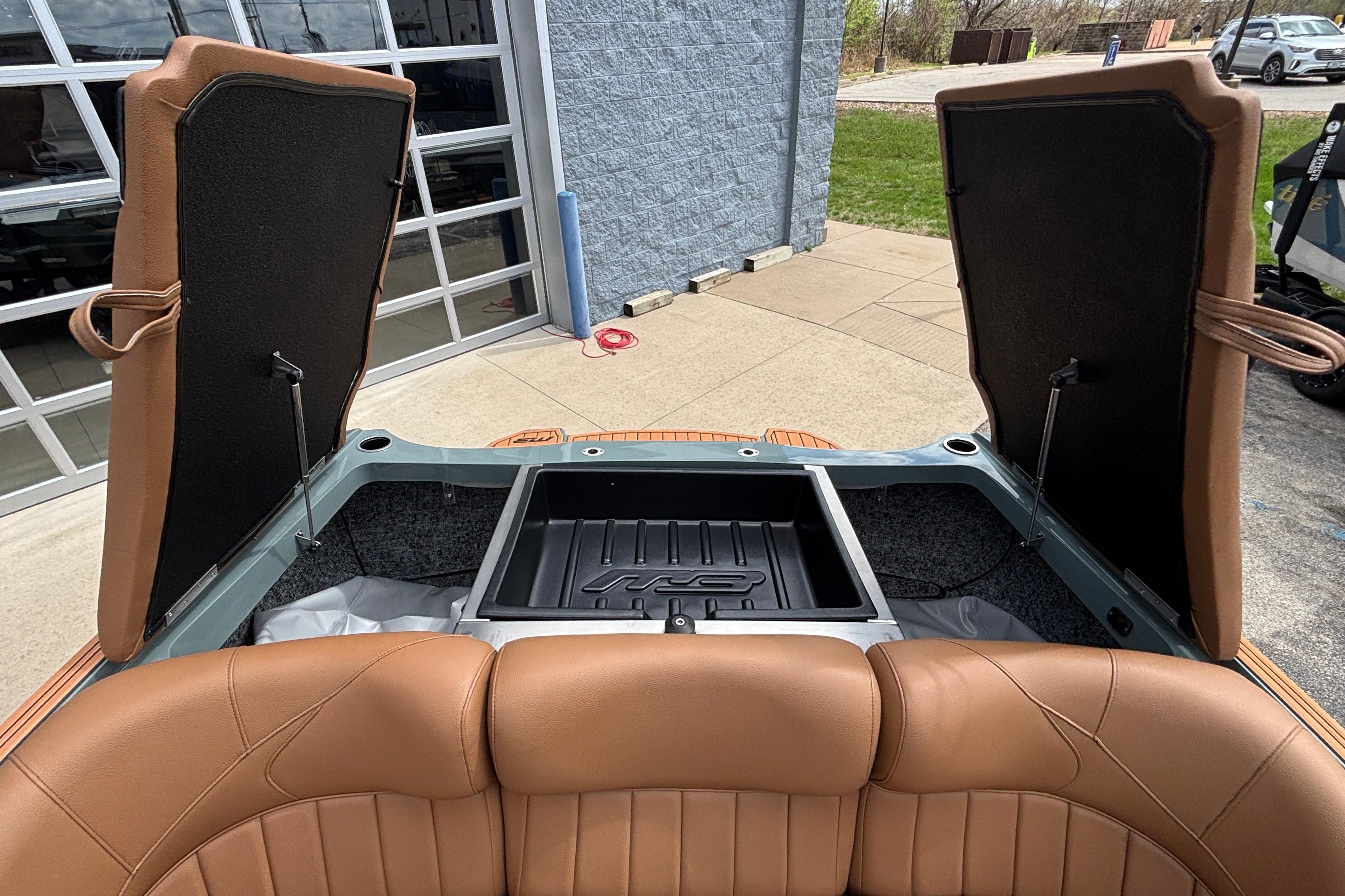 Open storage compartment of 2026 MB B52 23 Classic boat with brown leather seats.