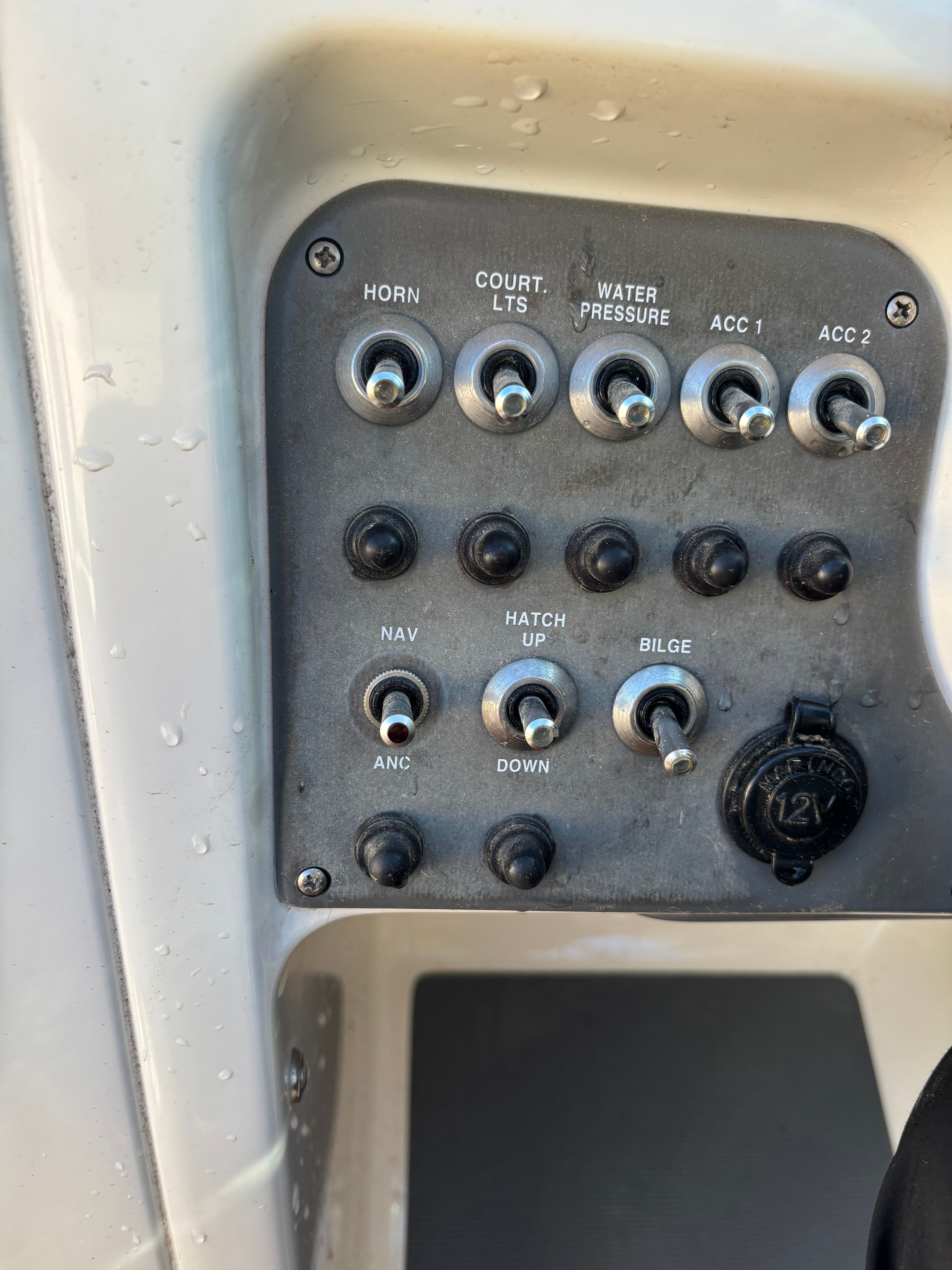 Control panel of a Chris-Craft Launch 22 boat with various switches and a 12V outlet.
