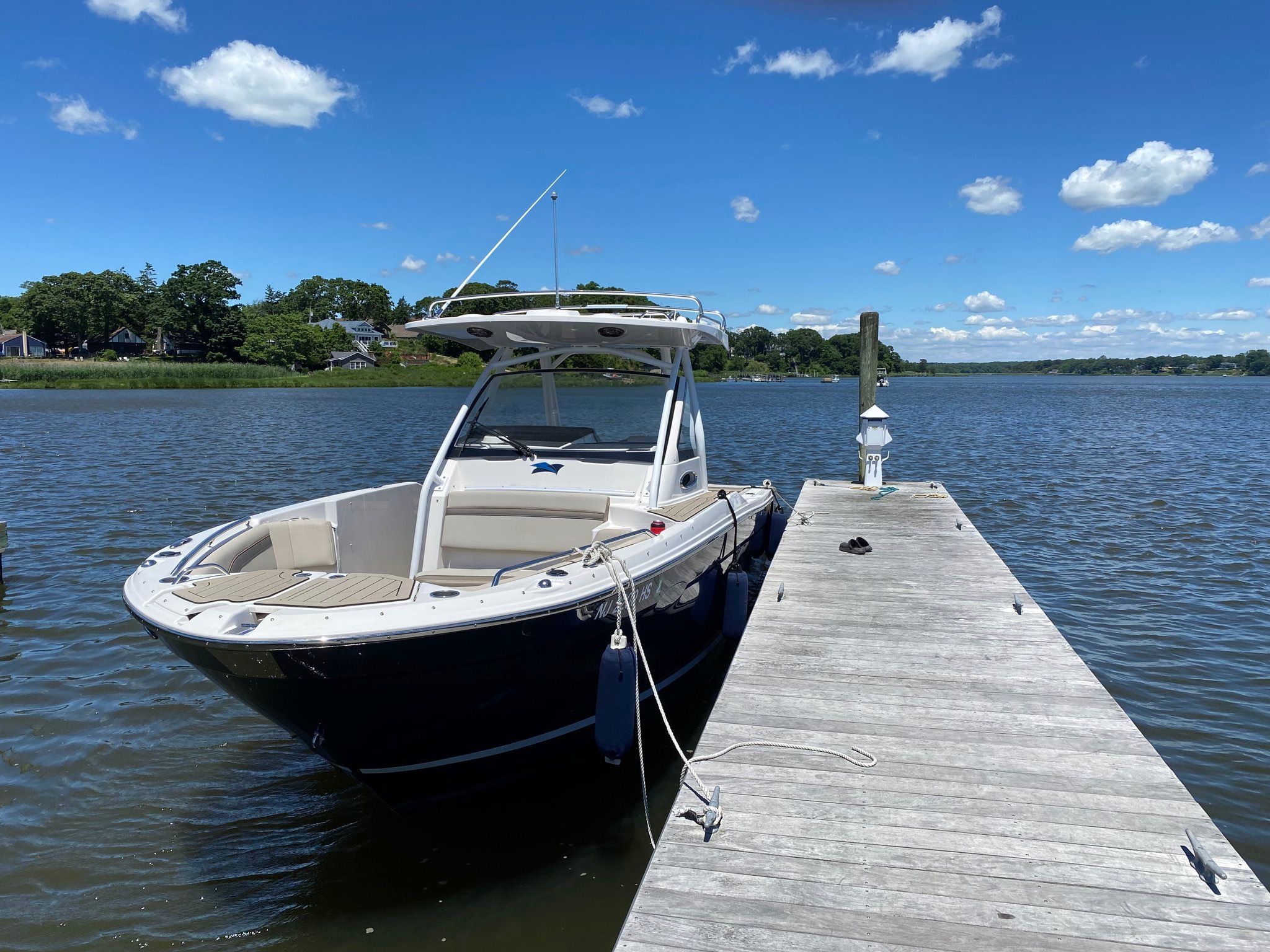A 2022 Cutwater C-24 CW docked at a wooden pier on calm water under a blue sky.