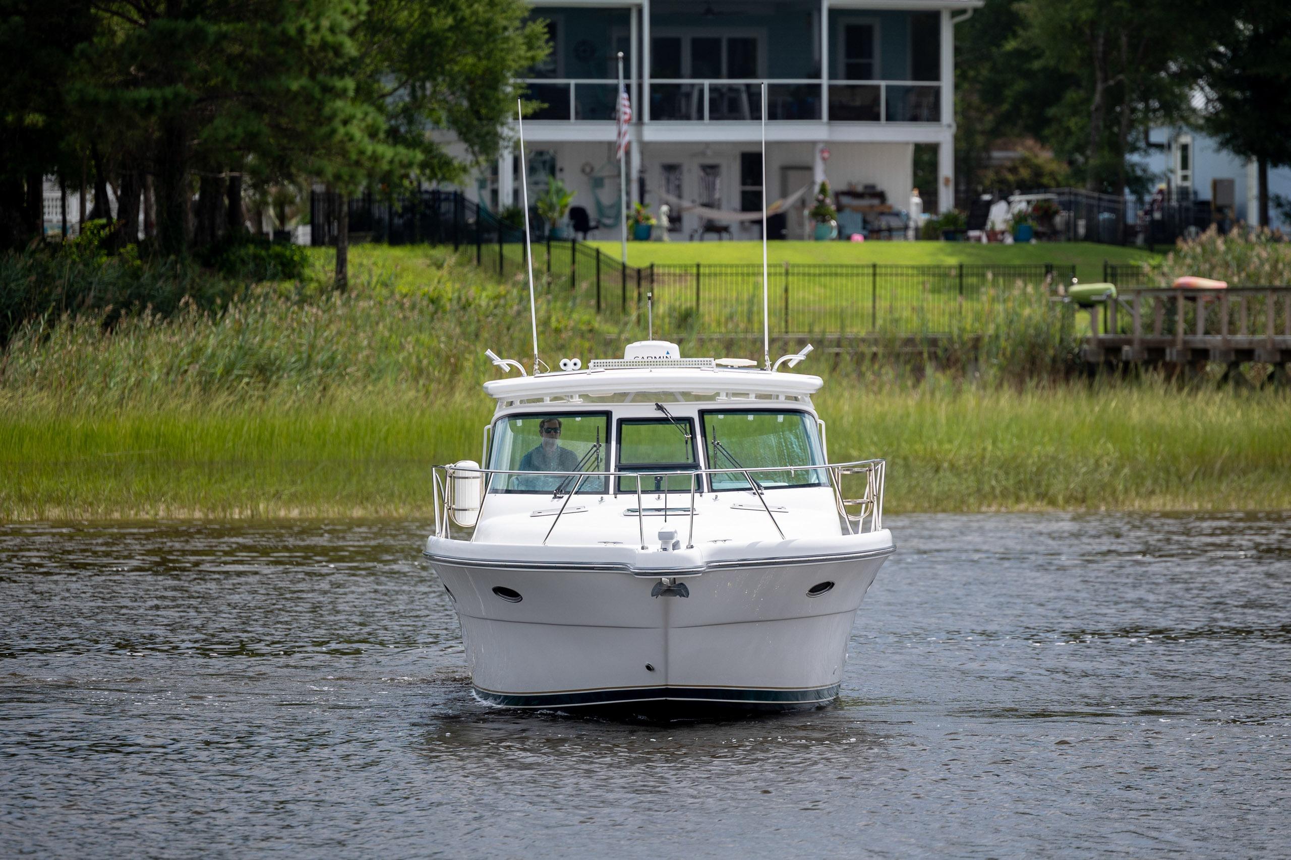 2004 Tiara Yachts 3200 Open cruising on a serene river near a waterfront home.