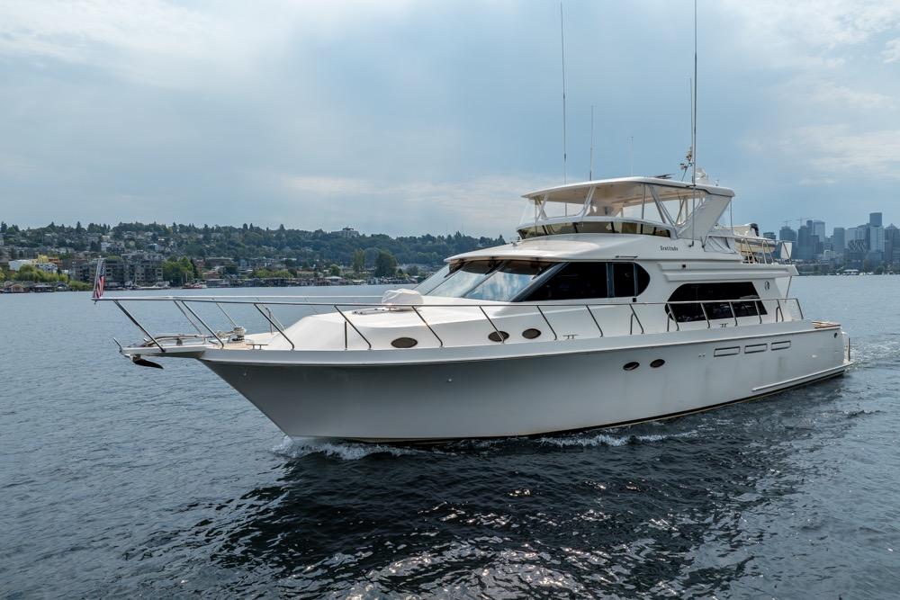 2005 Ocean Alexander 64 Motoryacht cruising on a calm waterway with cityscape background.