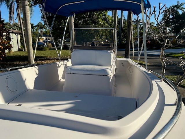 1994 Aquasport Osprey boat with blue canopy docked in harbor.