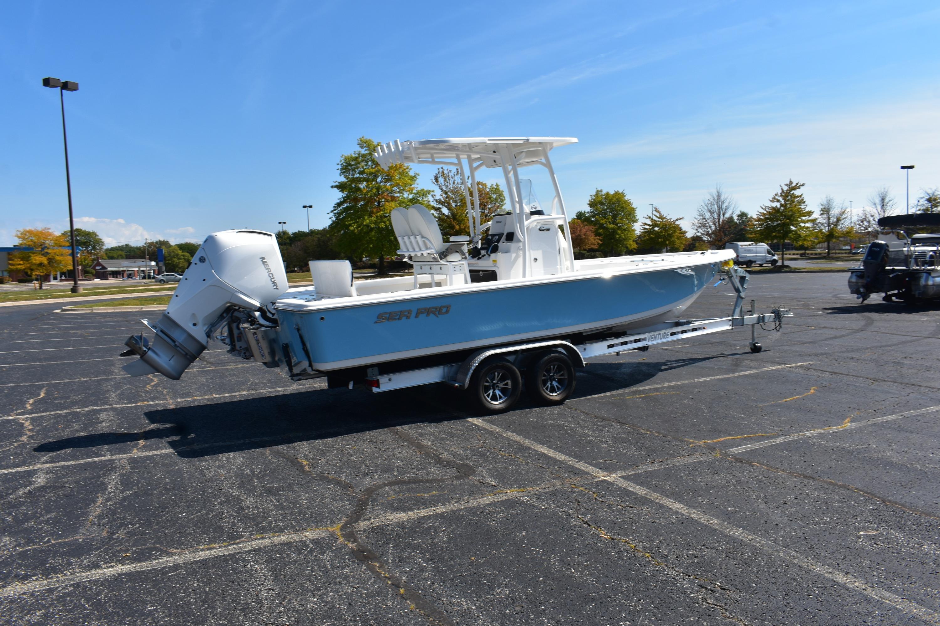 2025 Sea Pro 230 Bay boat on trailer in parking lot, clear sky background.