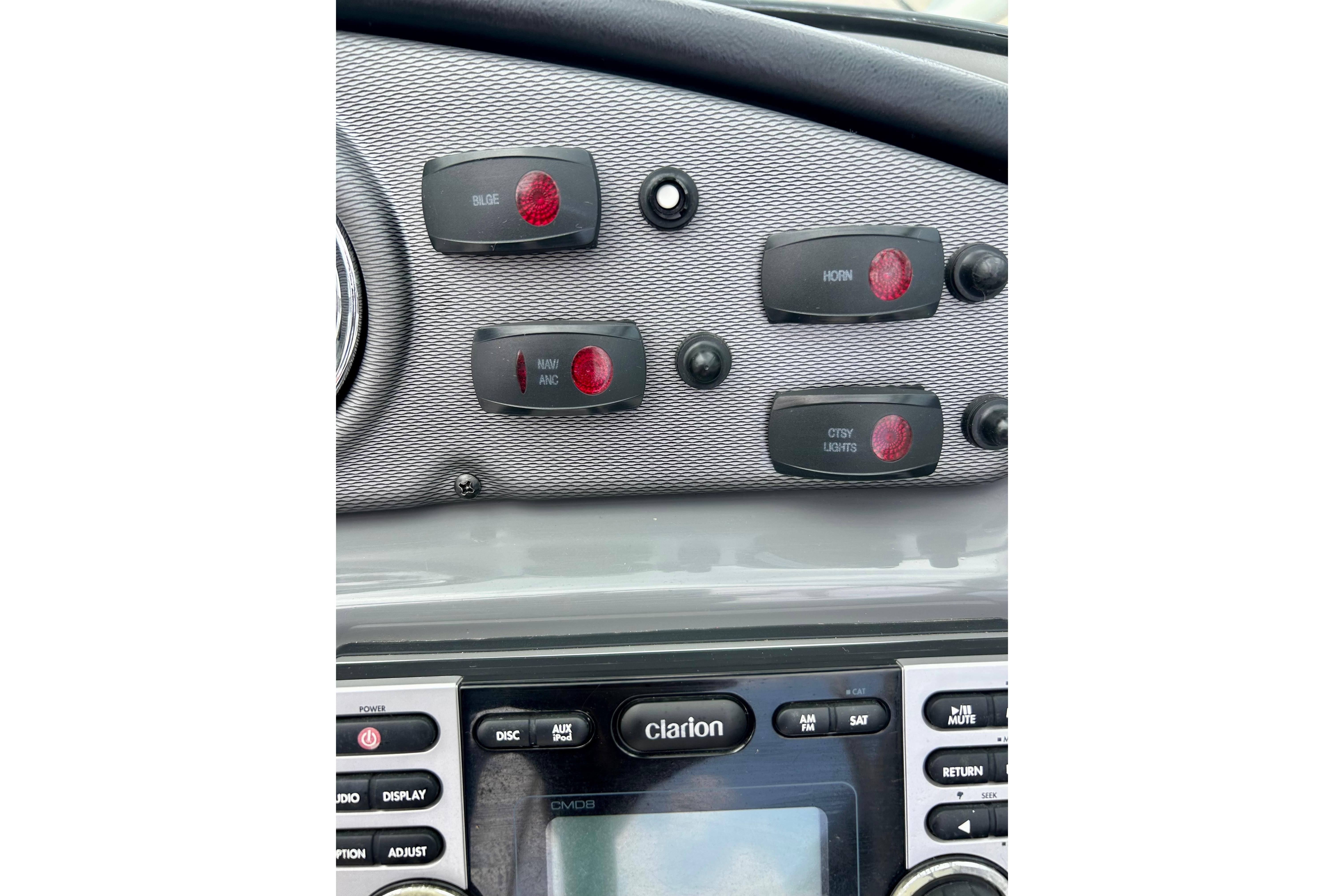 Control panel of a 2015 Yamaha Boats AR210 with switches and Clarion audio system.