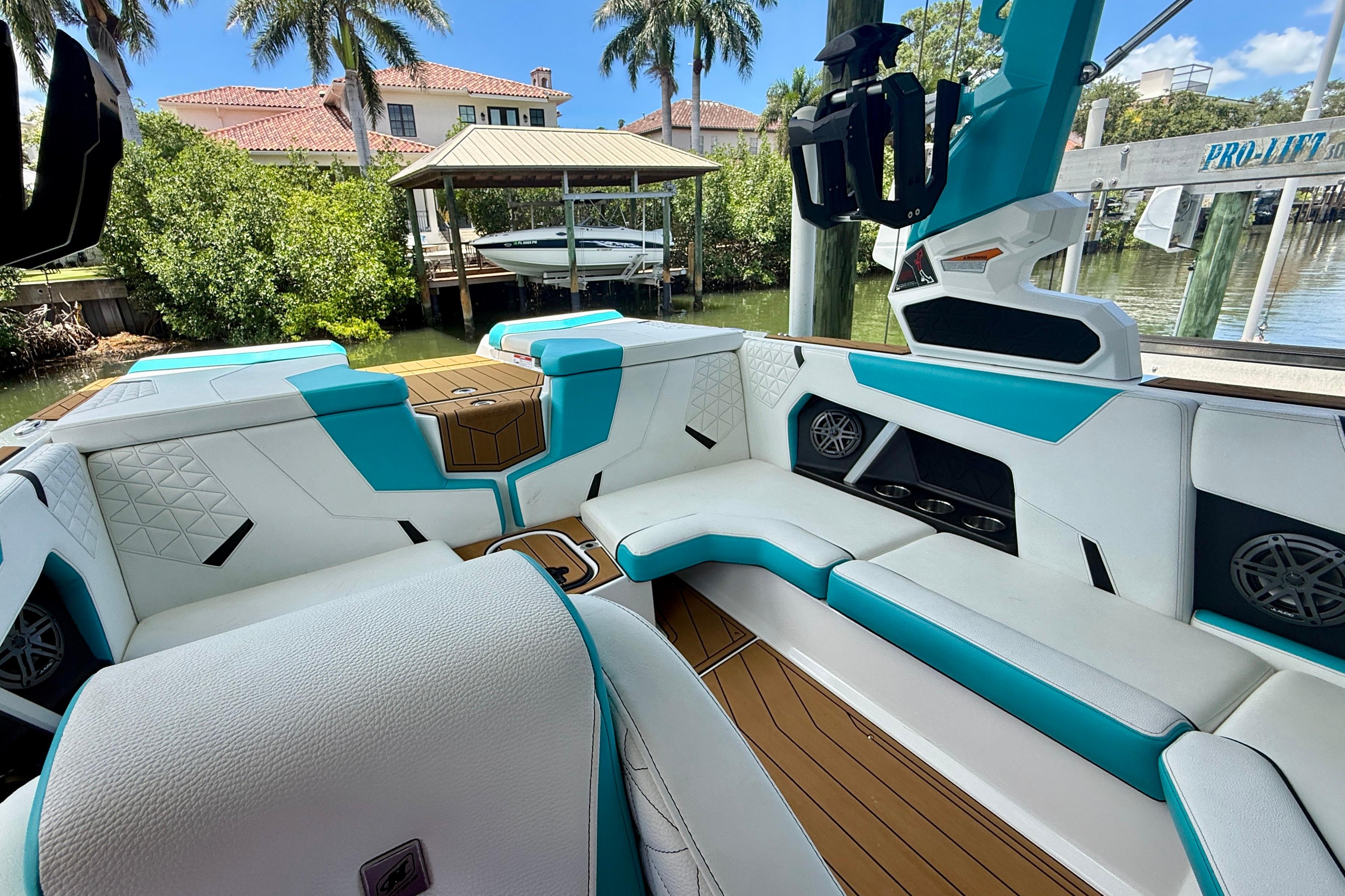 2024 Nautique Super Air Nautique GS20 interior with teal and white seating, docked near waterfront homes.