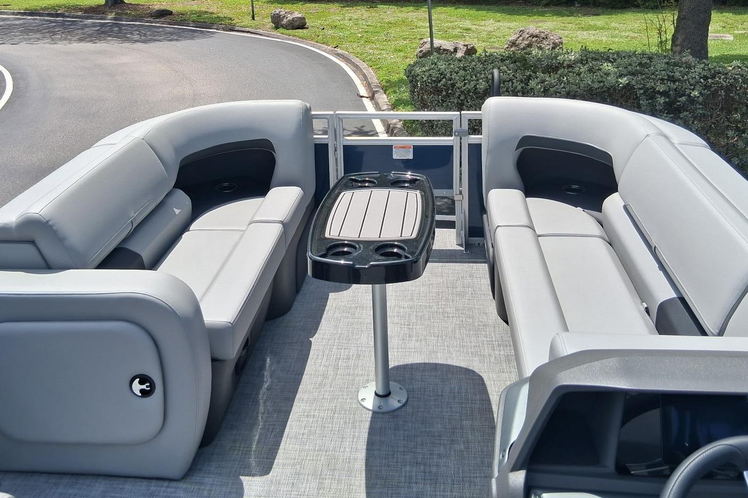 2026 Sun Tracker SportFish 22 DLX pontoon boat interior with gray seating and central table.