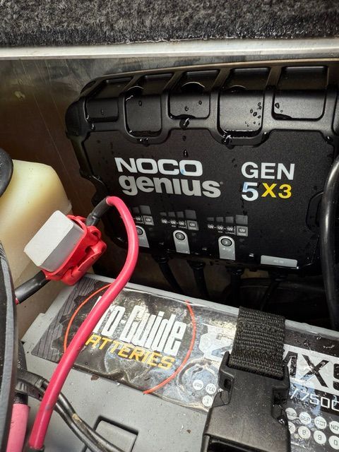 A NOCO Genius GEN 5X3 charger next to a Pro Guide battery in the boat.