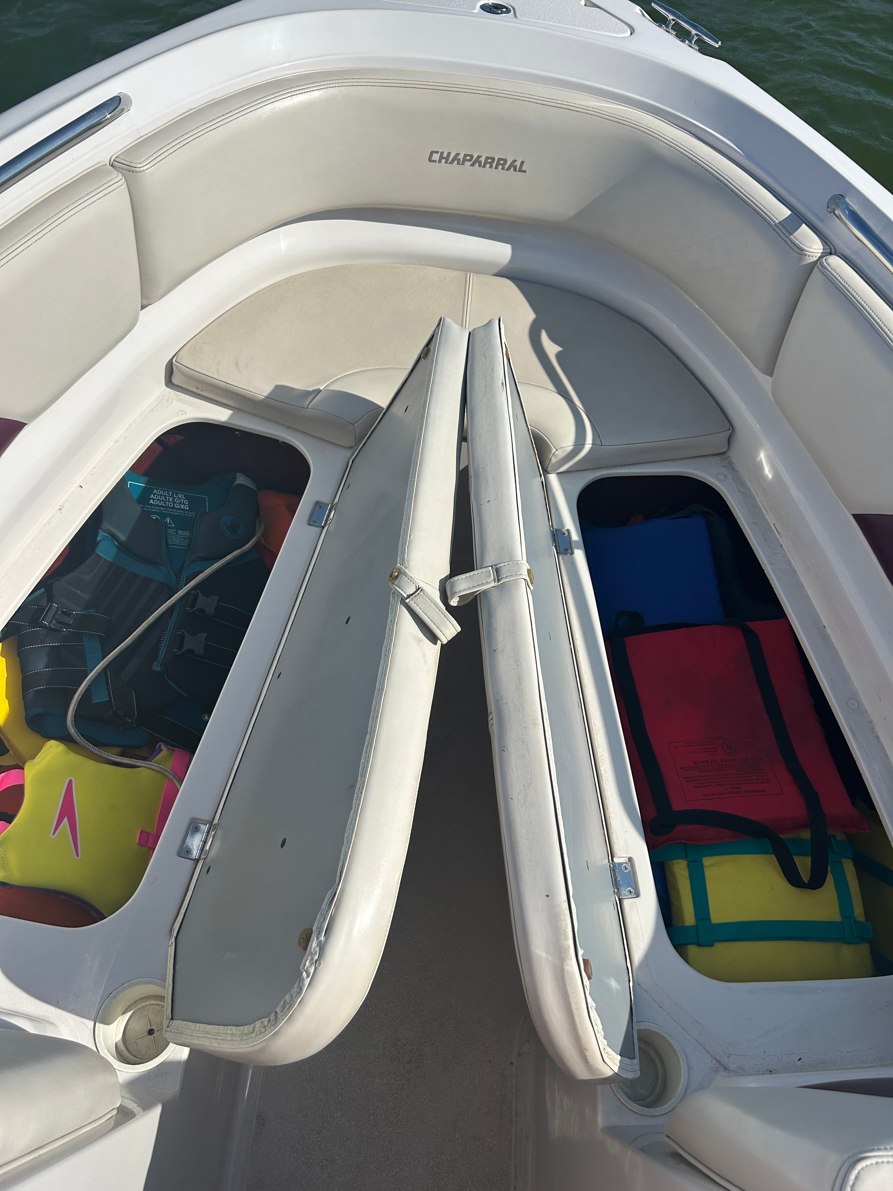 The image shows the bow of a Chaparral 2330 boat with storage compartments and life jackets.