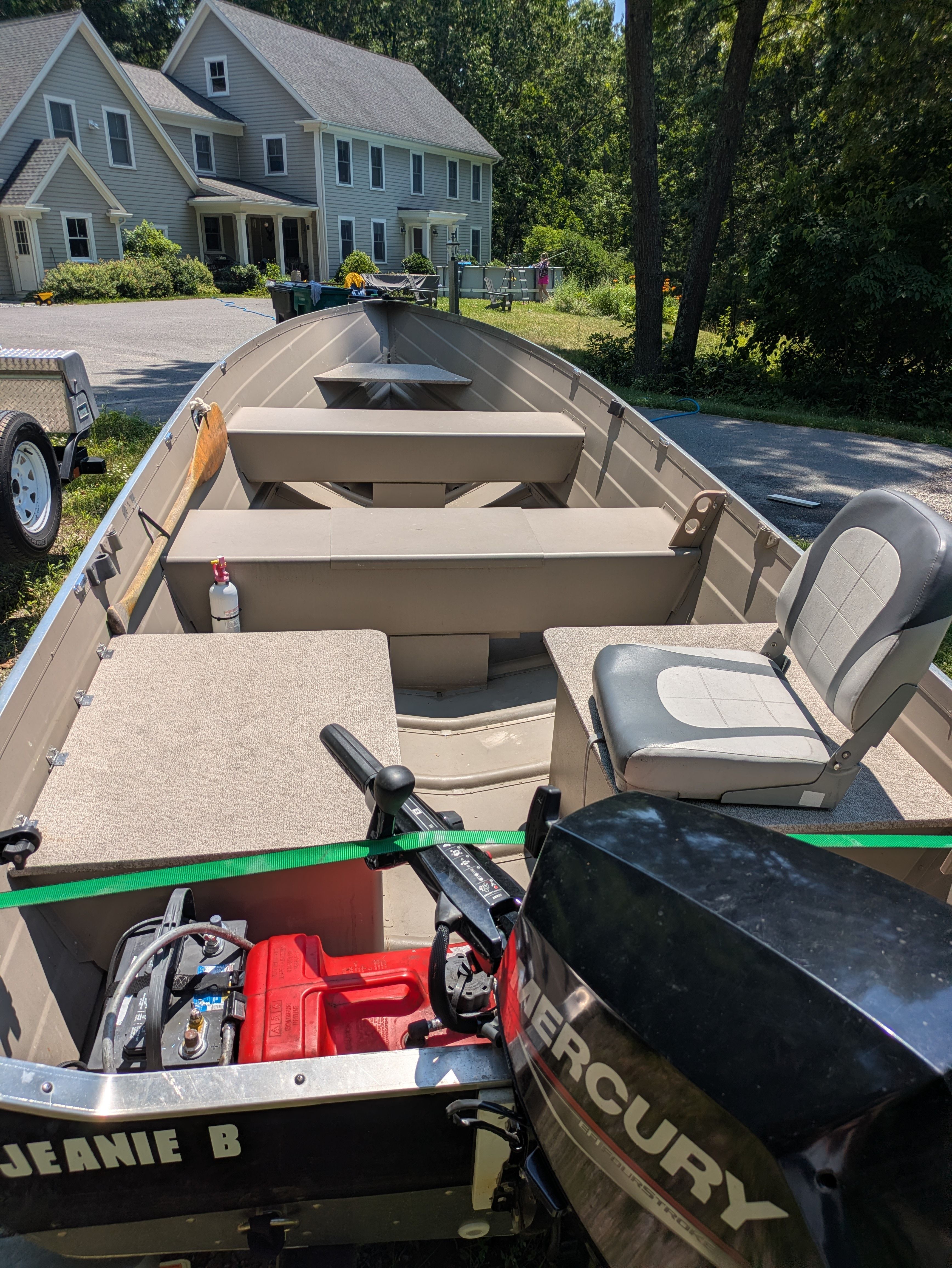 A 2023 Custom Voyager boat on a trailer in front of a house.