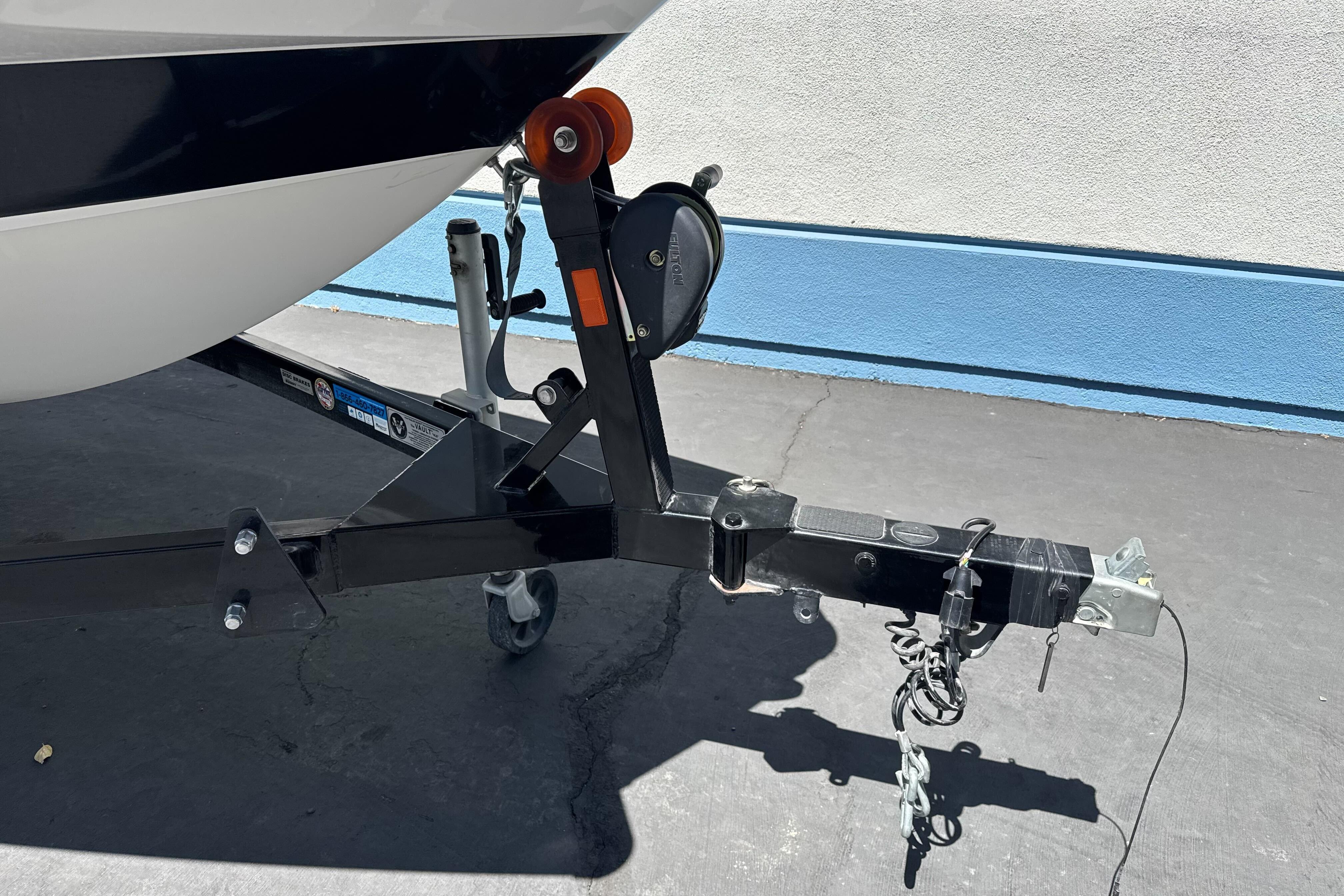 Trailer hitch of a 2015 Axis A20 boat on pavement.