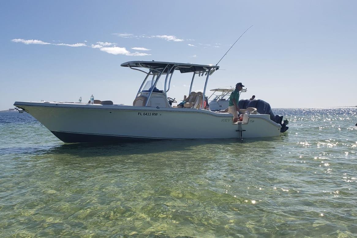 2019 Key West 263 FS boat anchored in clear, shallow water under a sunny sky.