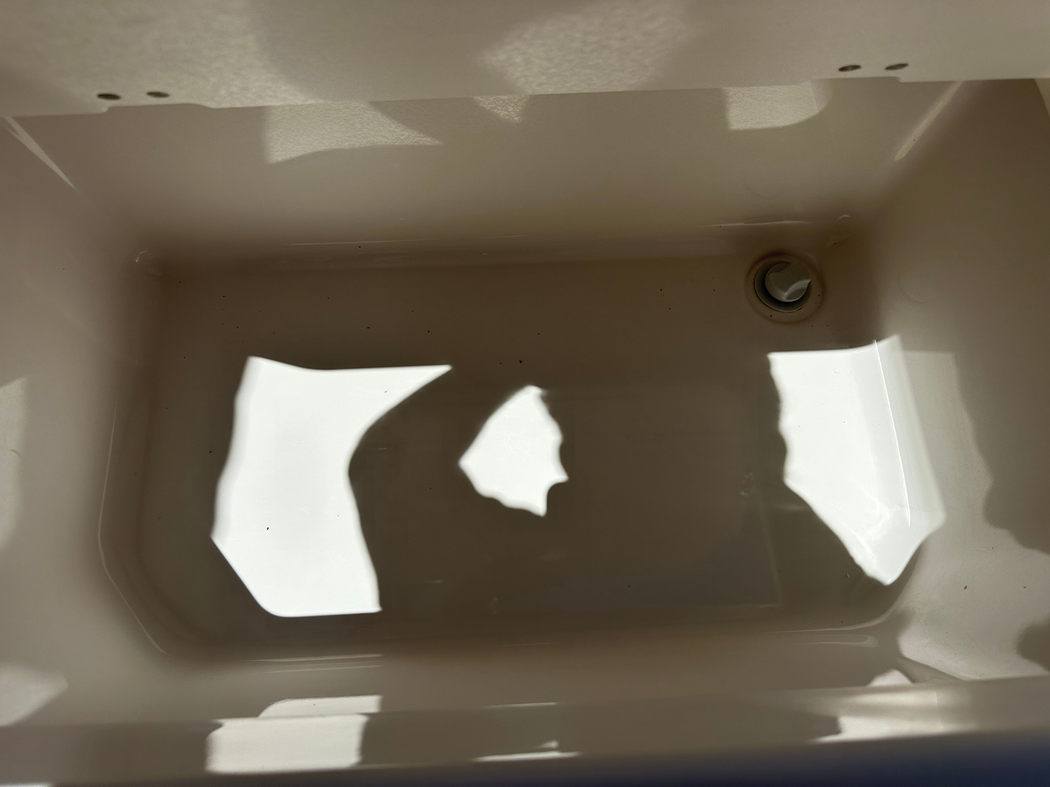 An empty rectangular compartment with a drain hole at one end.