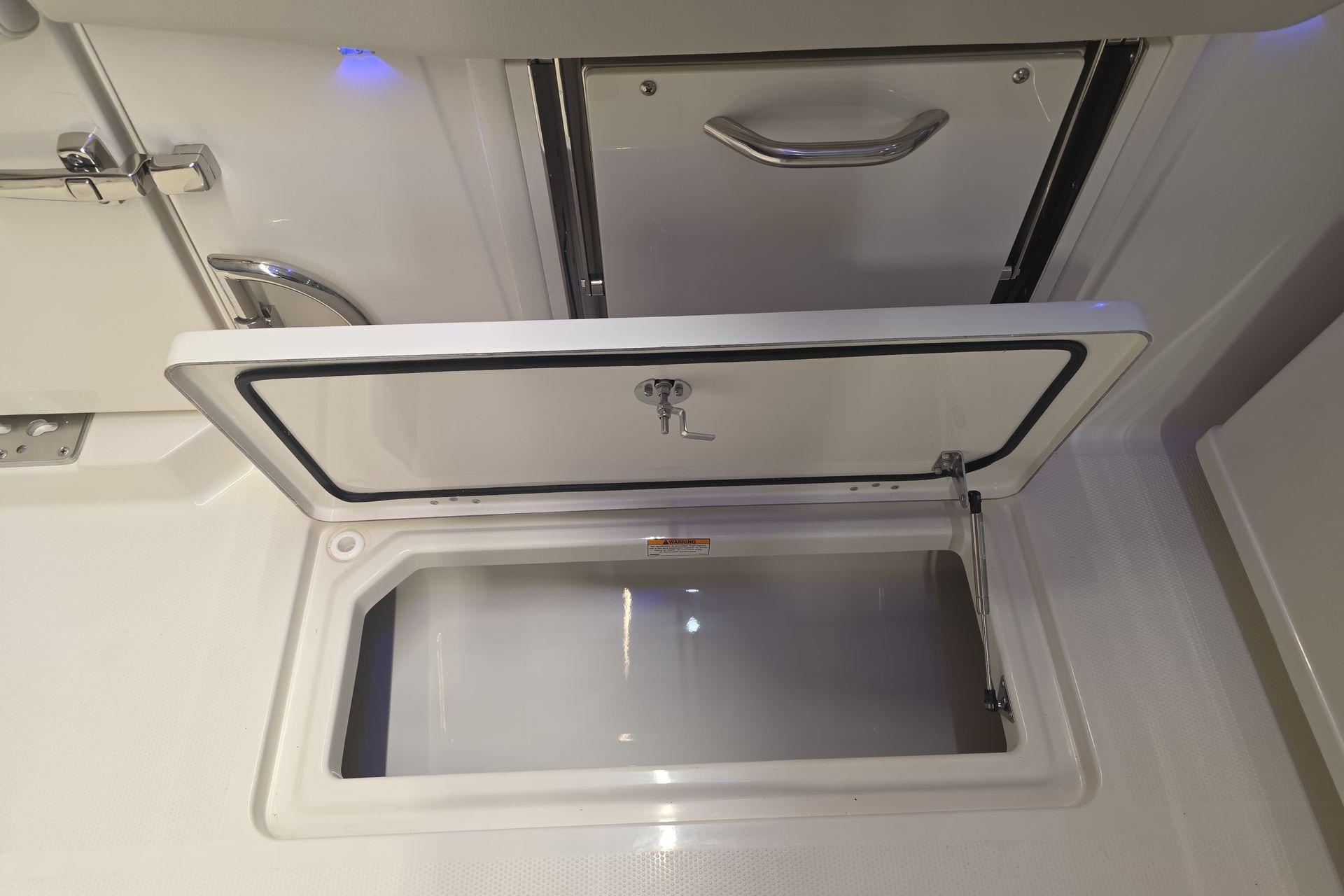 Open storage compartment on 2026 Sailfish 316 DC boat, showcasing sleek design and functionality.