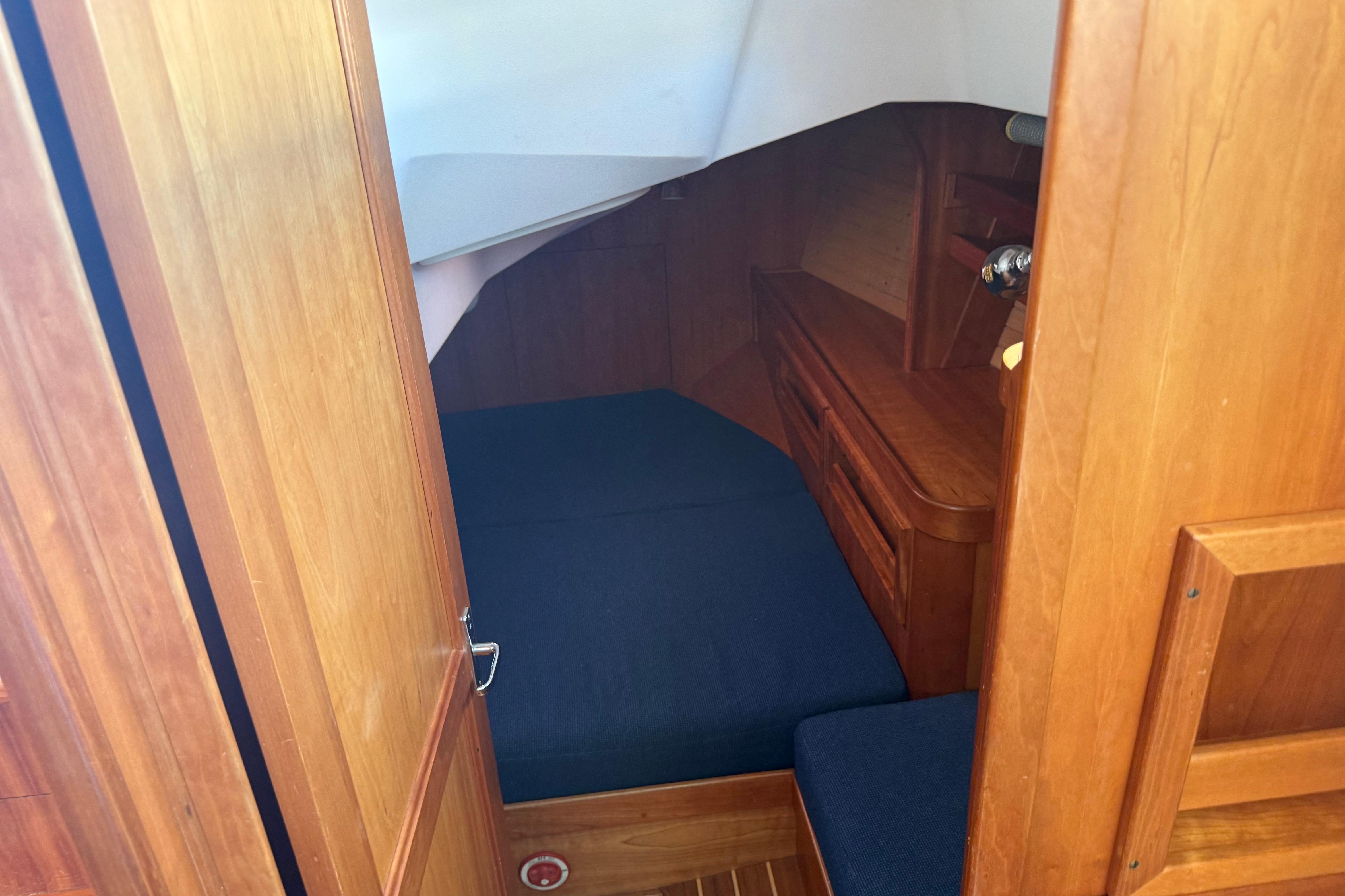 Interior cabin of a 2004 Sabre 386 sailboat with wooden finish and blue cushions.