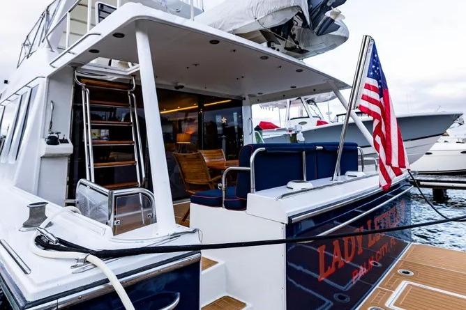 2000 Pacific Mariner 65 Motoryacht docked, featuring American flag and elegant seating area.