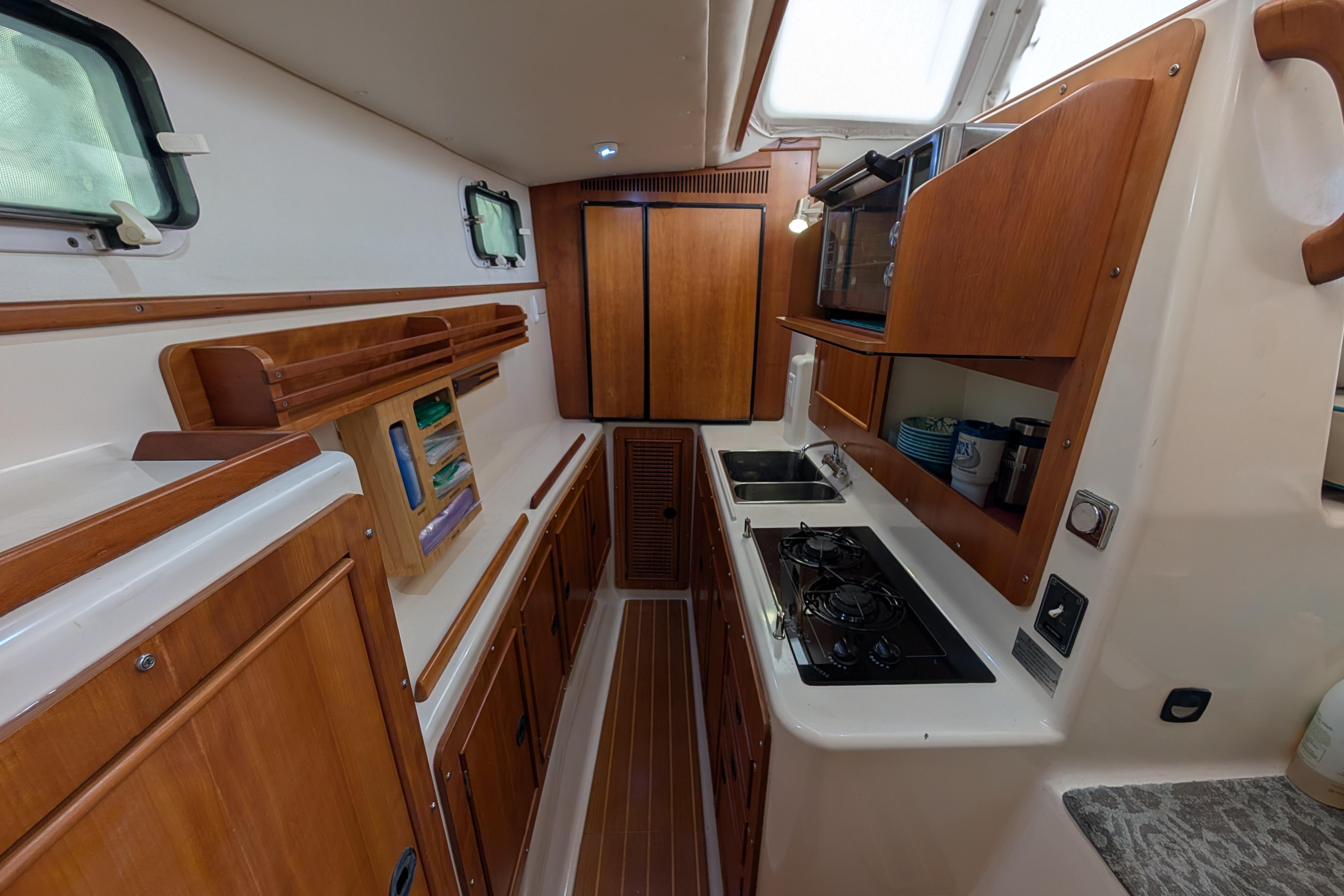 2004 PDQ 34 Powercat interior kitchen with wooden cabinetry and modern appliances.
