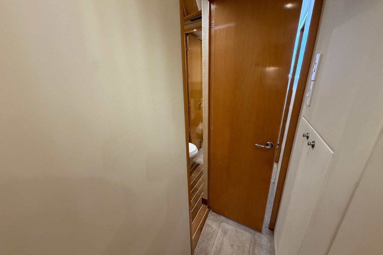 Interior view of 2003 Hatteras 54 Convertible yacht bathroom with wooden door and flooring.