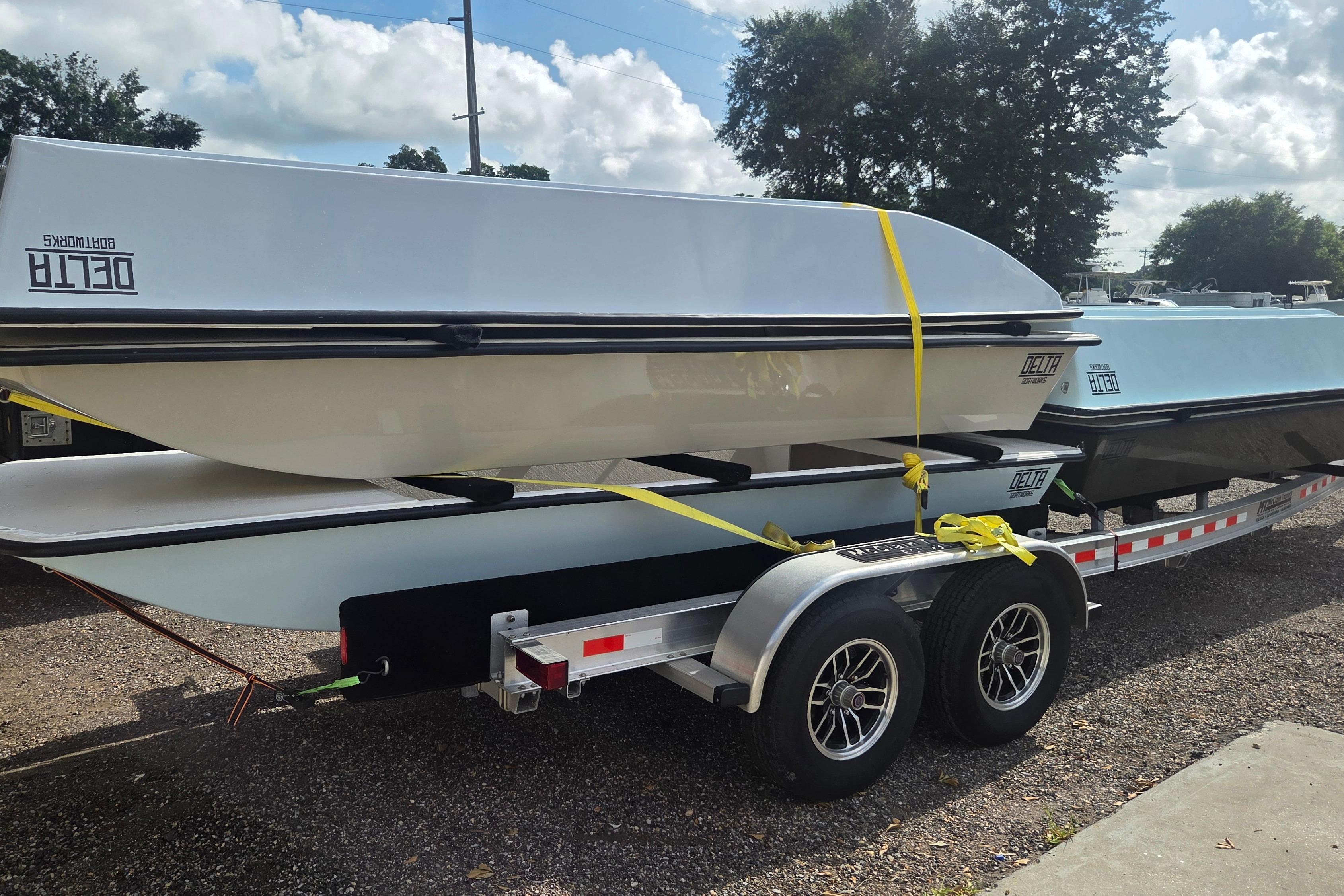 2027 Delta Boatworks 1550 on trailer, secured with yellow straps, under a cloudy sky.