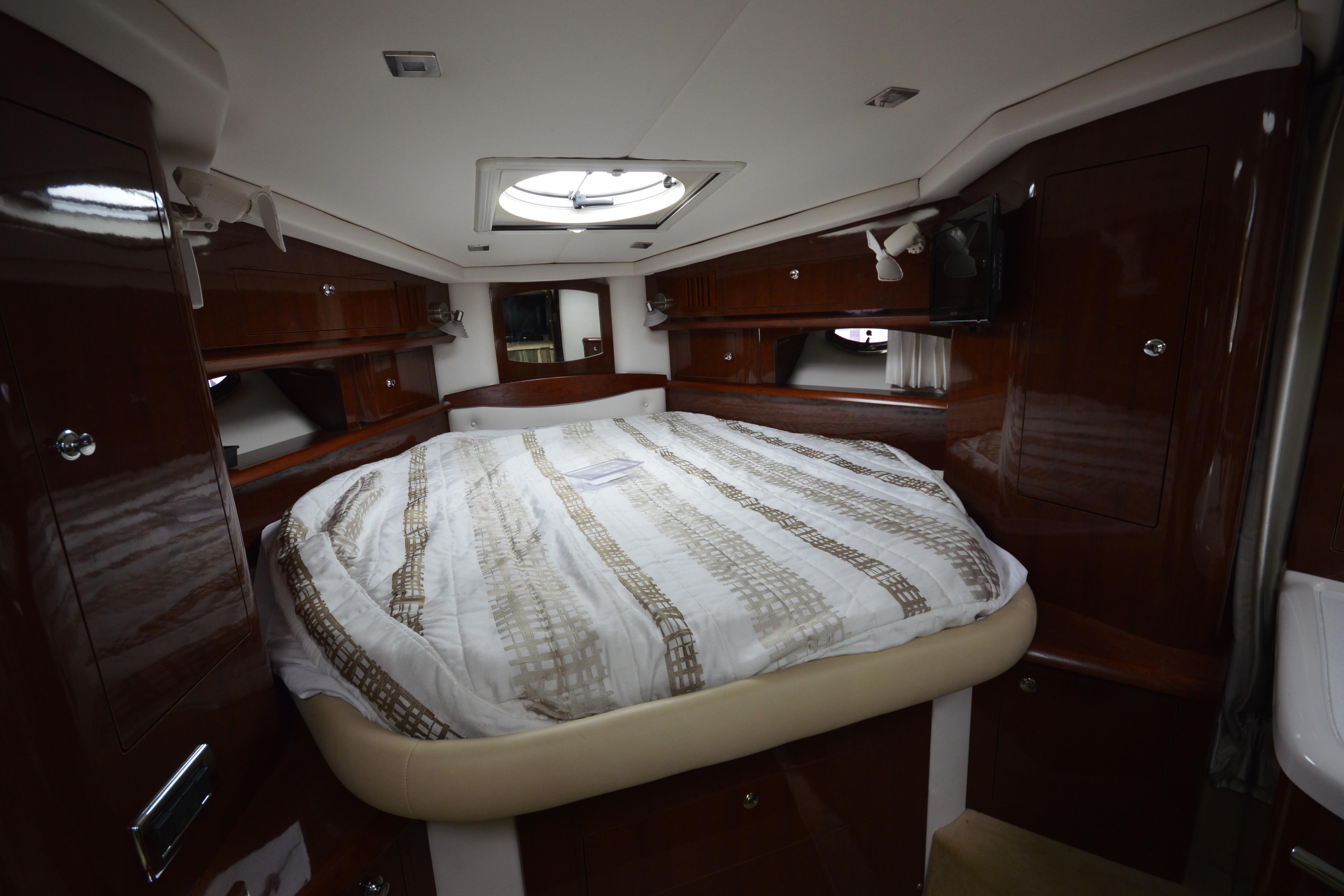 Luxurious cabin interior of 2013 Four Winns V375 yacht with cozy bed and wooden finish.