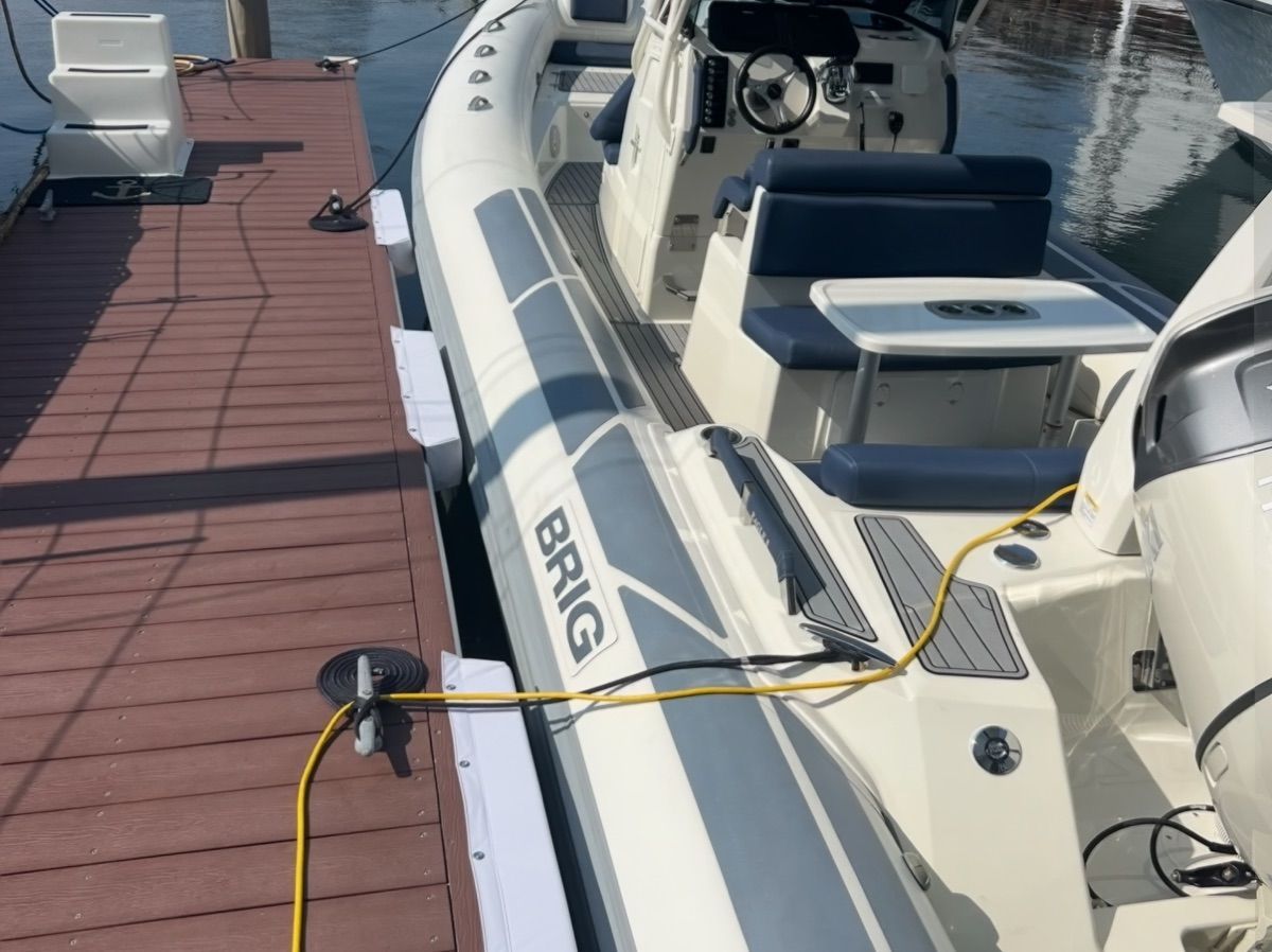 A modern inflatable boat with blue seating and helm, docked at a wooden pier.