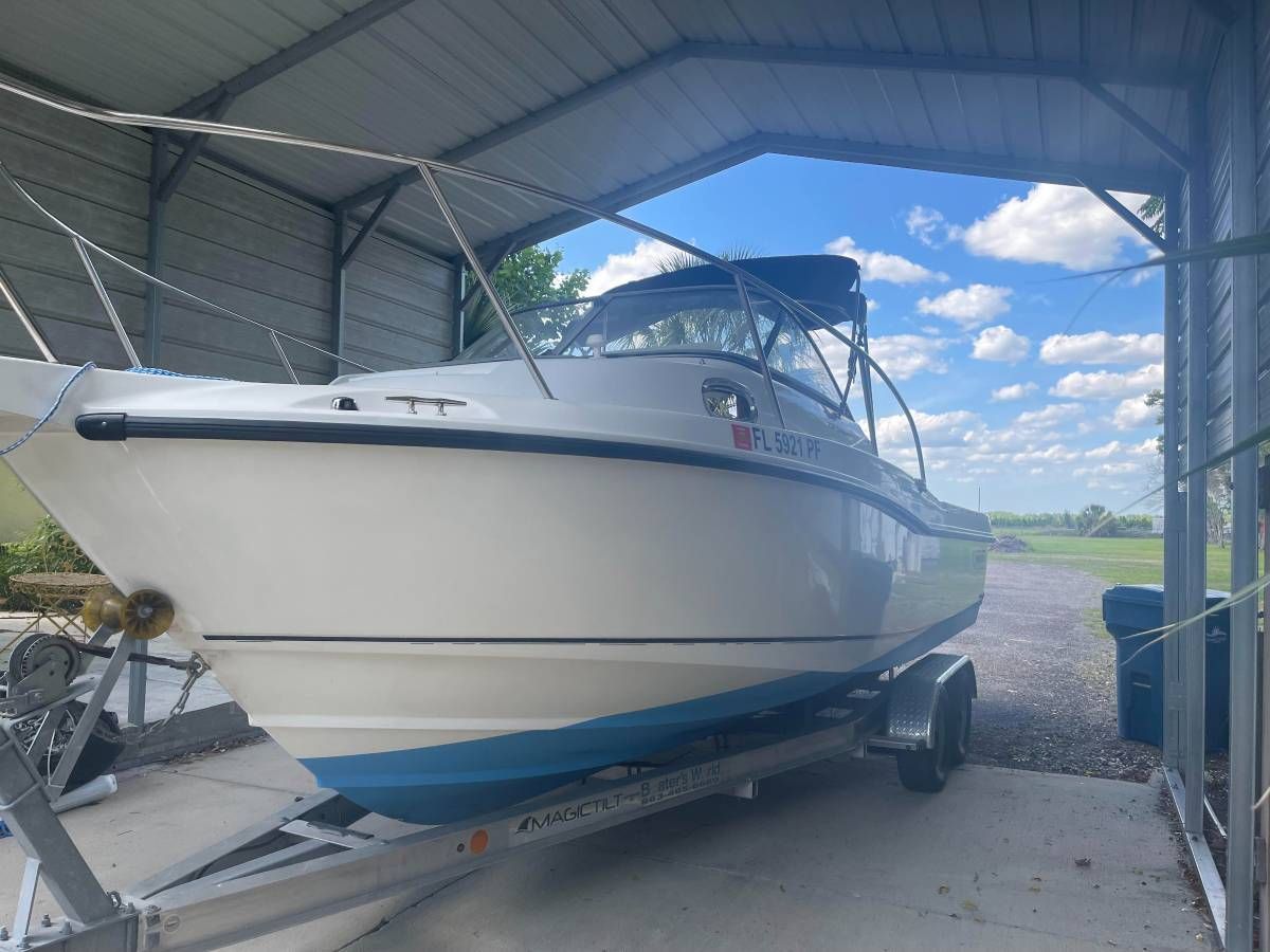 2010 Boston Whaler 235 Conquest boat on trailer under carport.