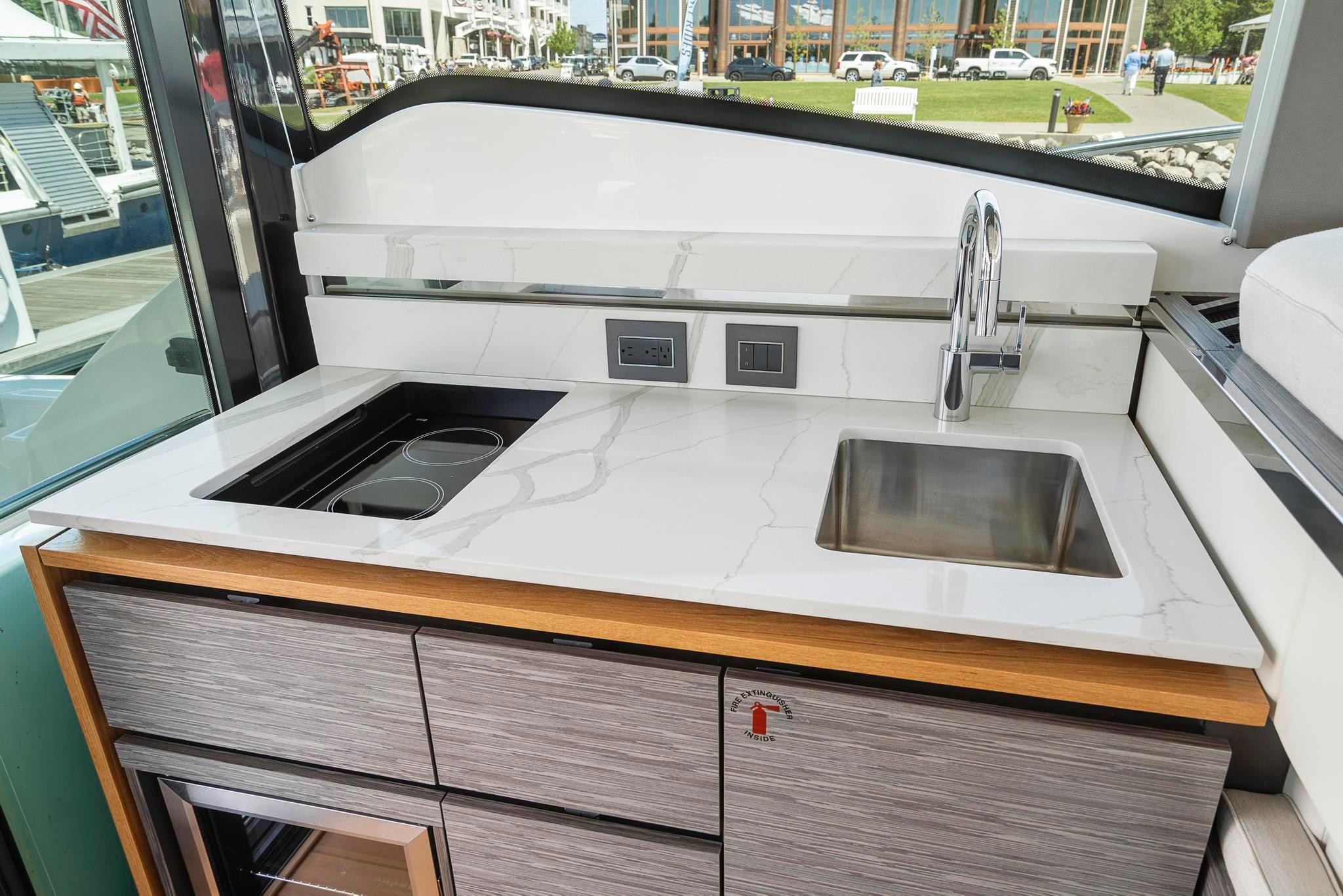 2022 Tiara Yachts C49 Coupe kitchen area with sink and stovetop, modern design.