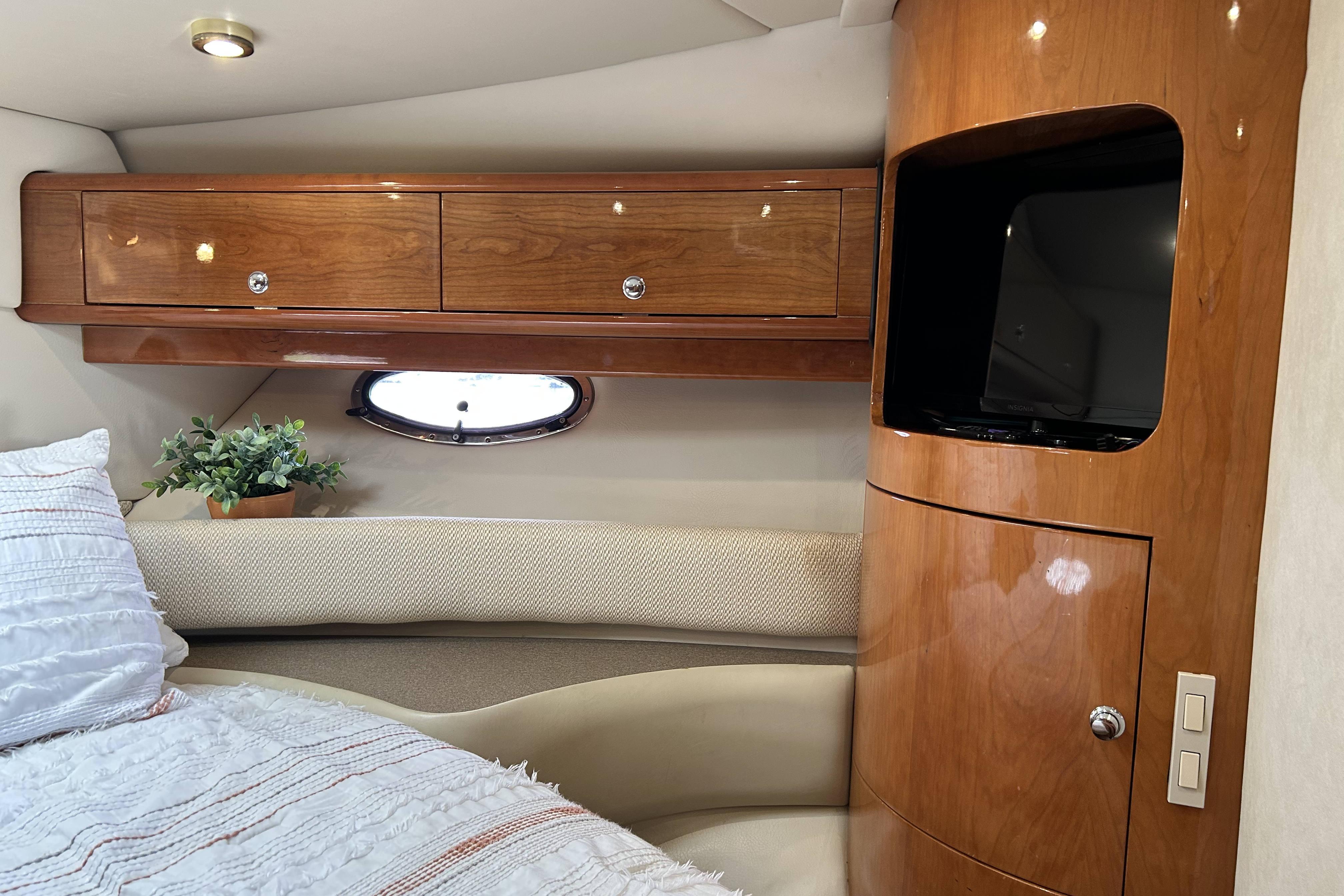 Luxurious cabin interior of 2002 Regal Commodore 4260 yacht with wood cabinetry and cozy bedding.