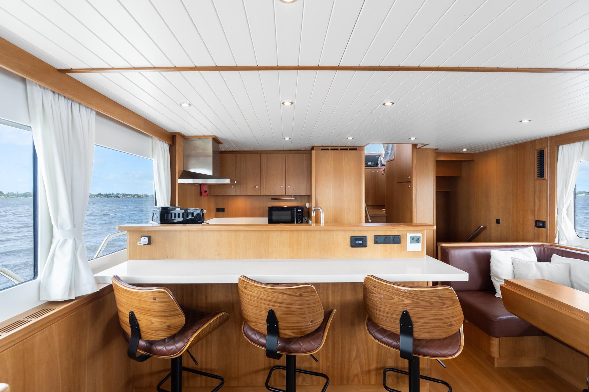 Luxurious interior of 2022 Alm Trawler Delfino 64 yacht with modern kitchen and seating area.