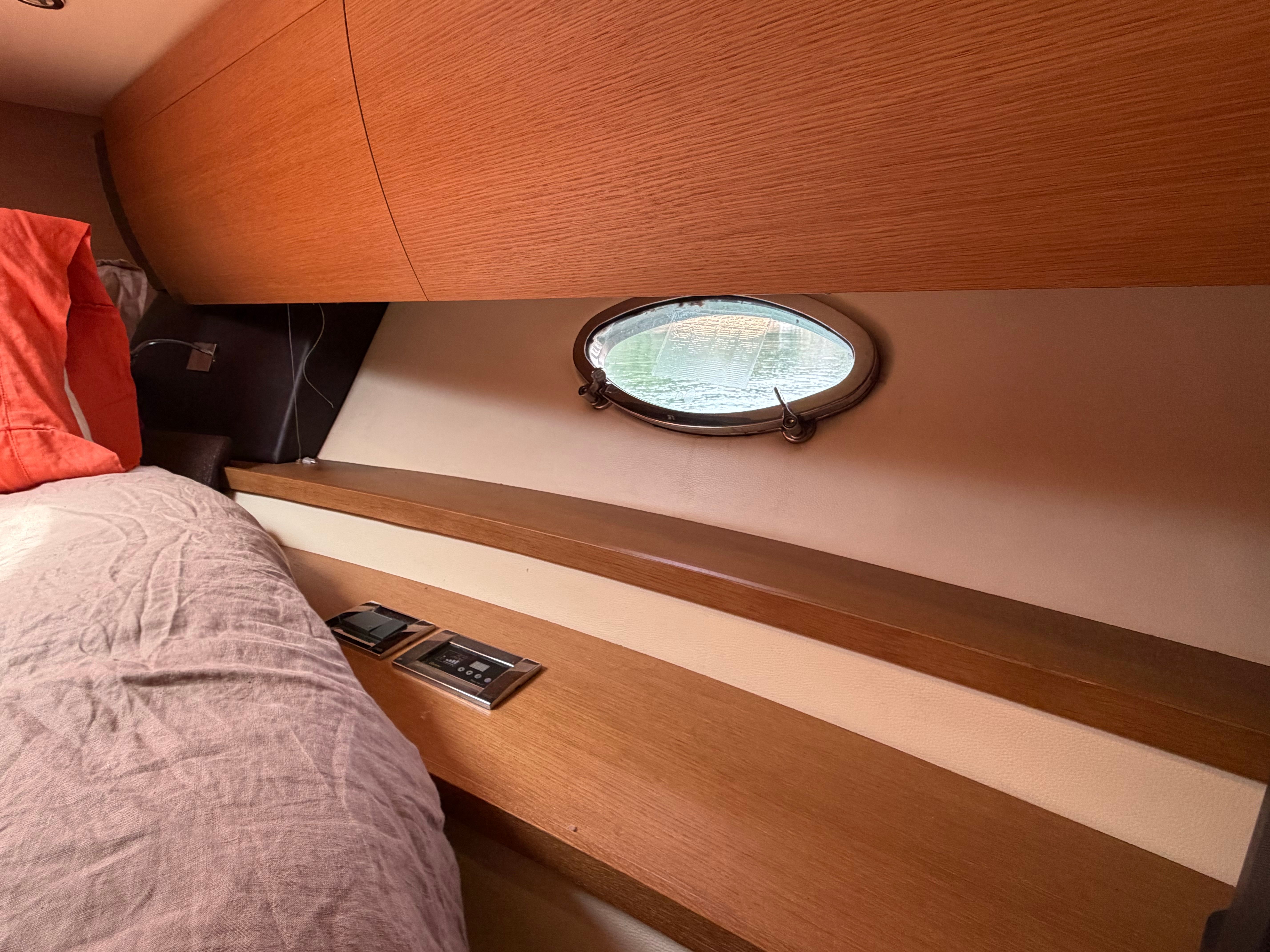 Interior of a 2011 Azimut Atlantis 40 with wooden walls and a porthole.